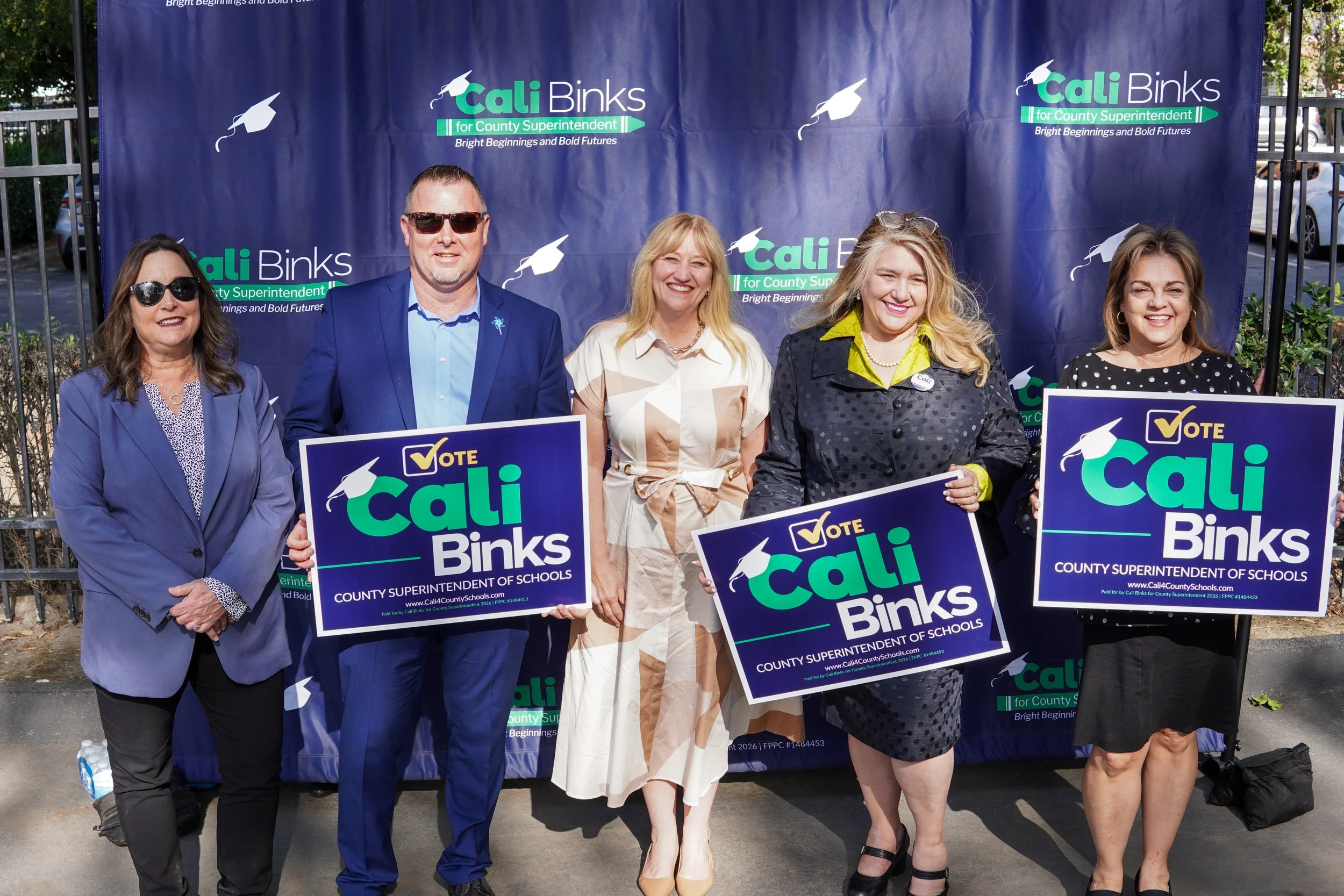 Four adults holding yard signs and Cal Binks standing in the middle of the row.
