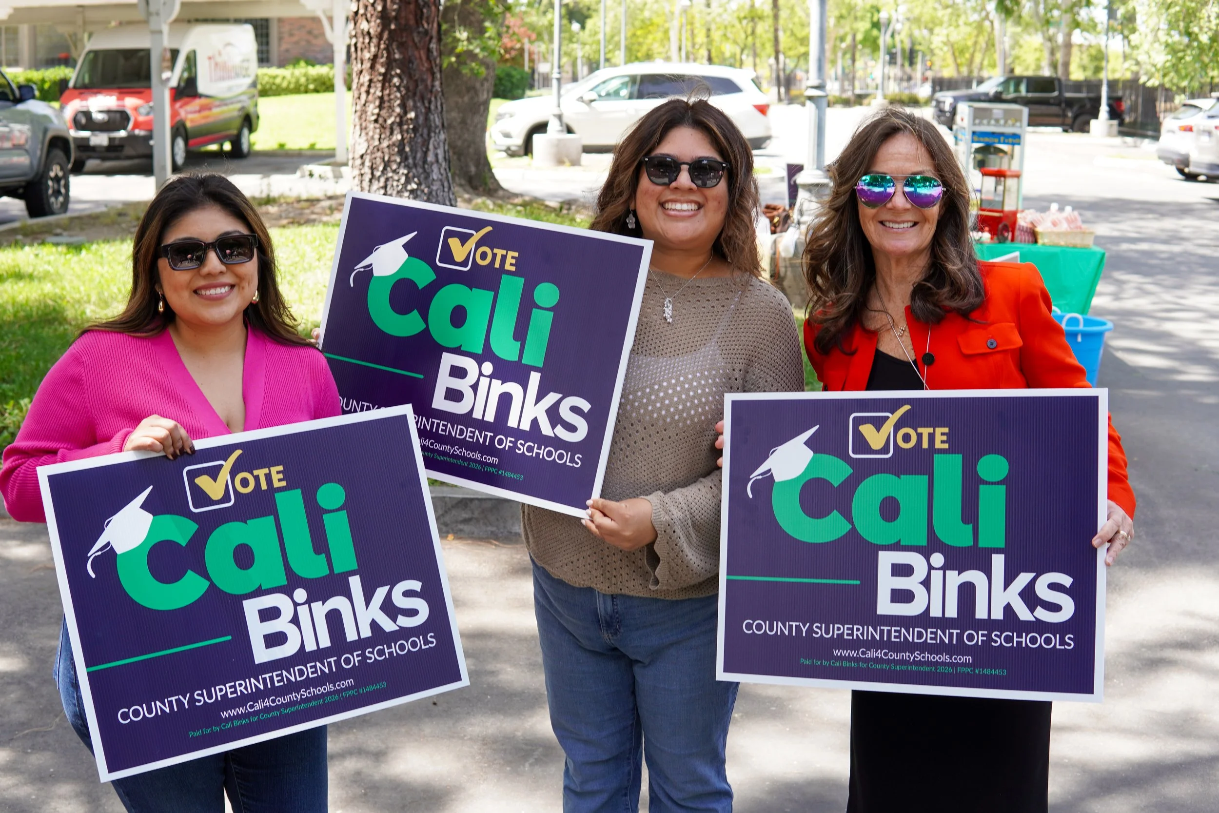 Three adults holding yard signs.