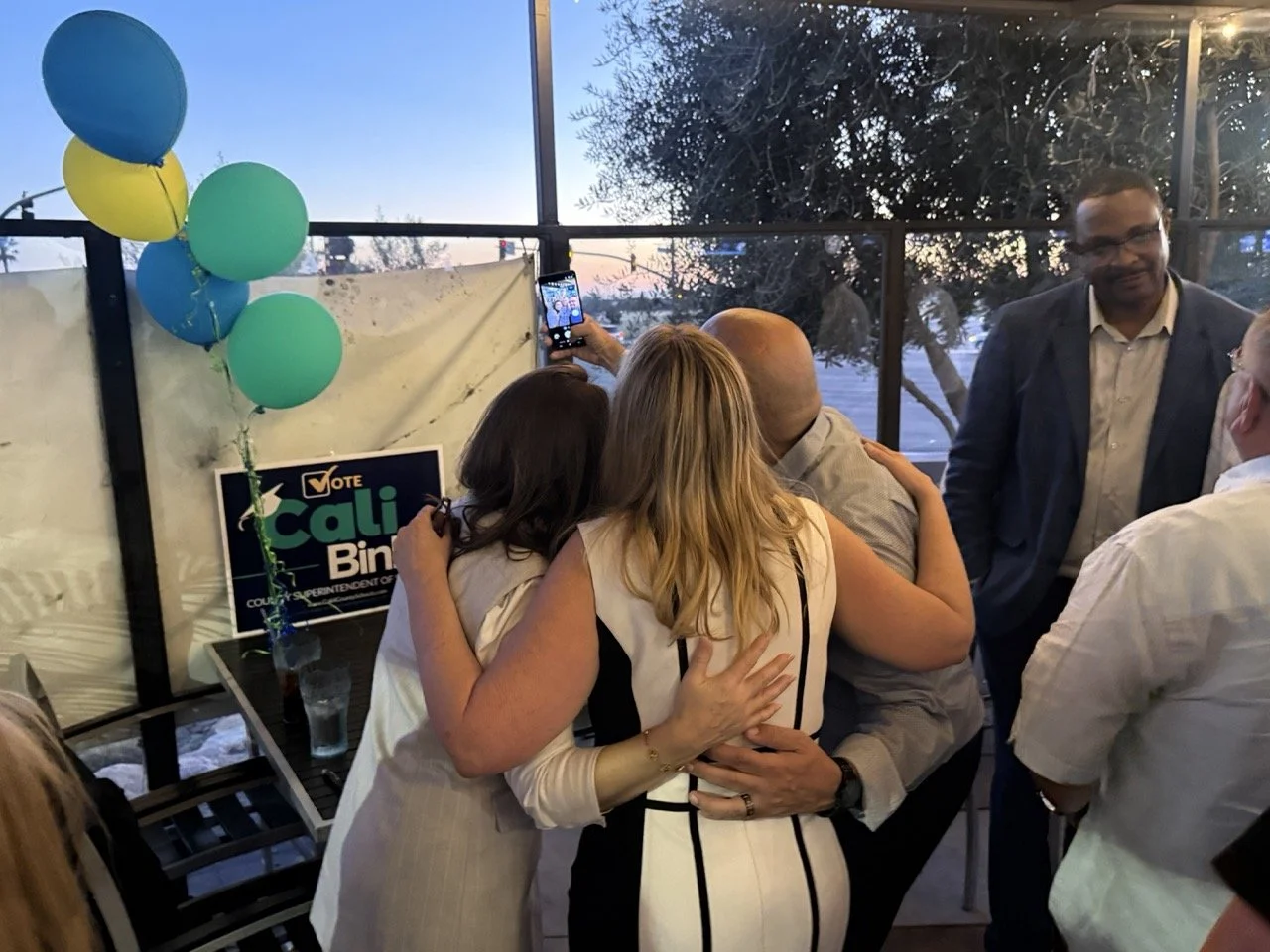 Cali taking a selfie with two guests.