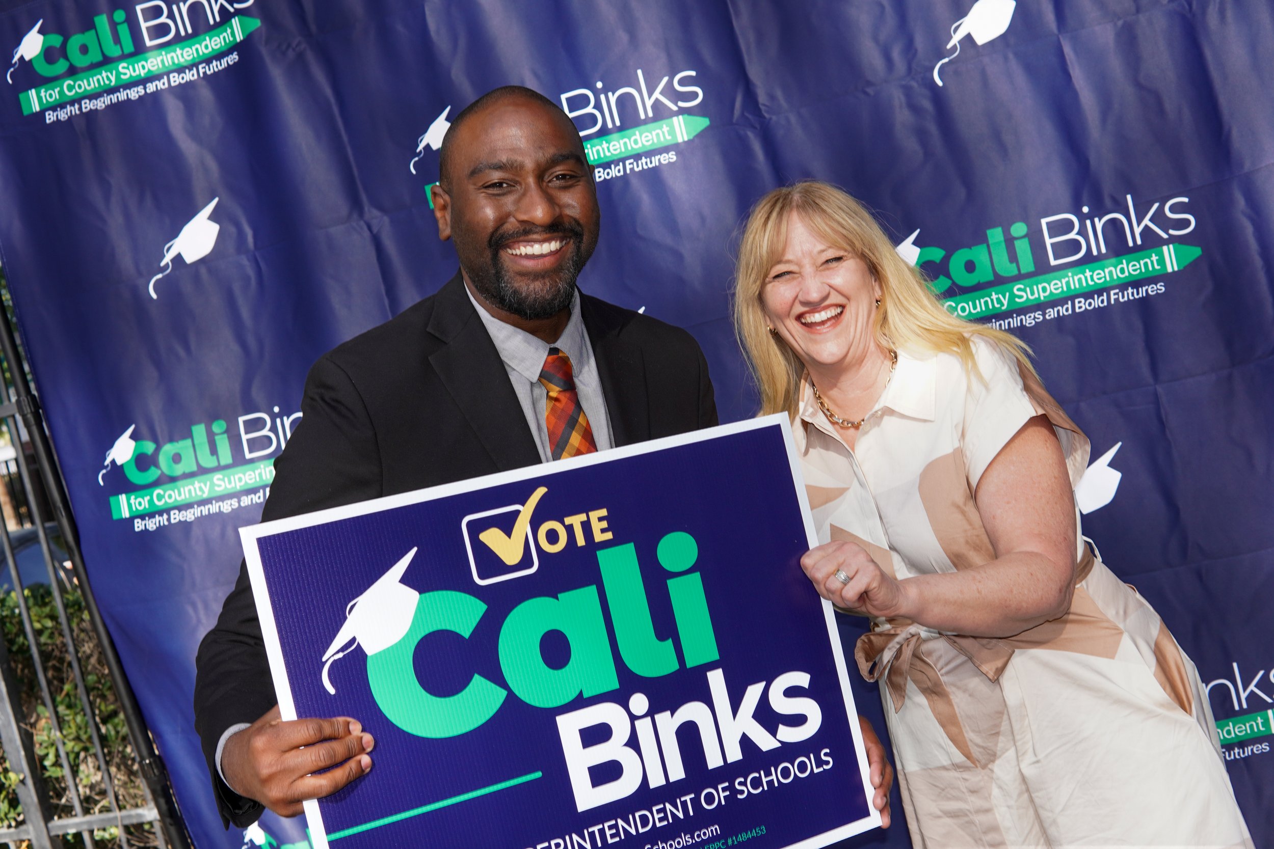 Adult holding a yard sign next to Cali Binks.