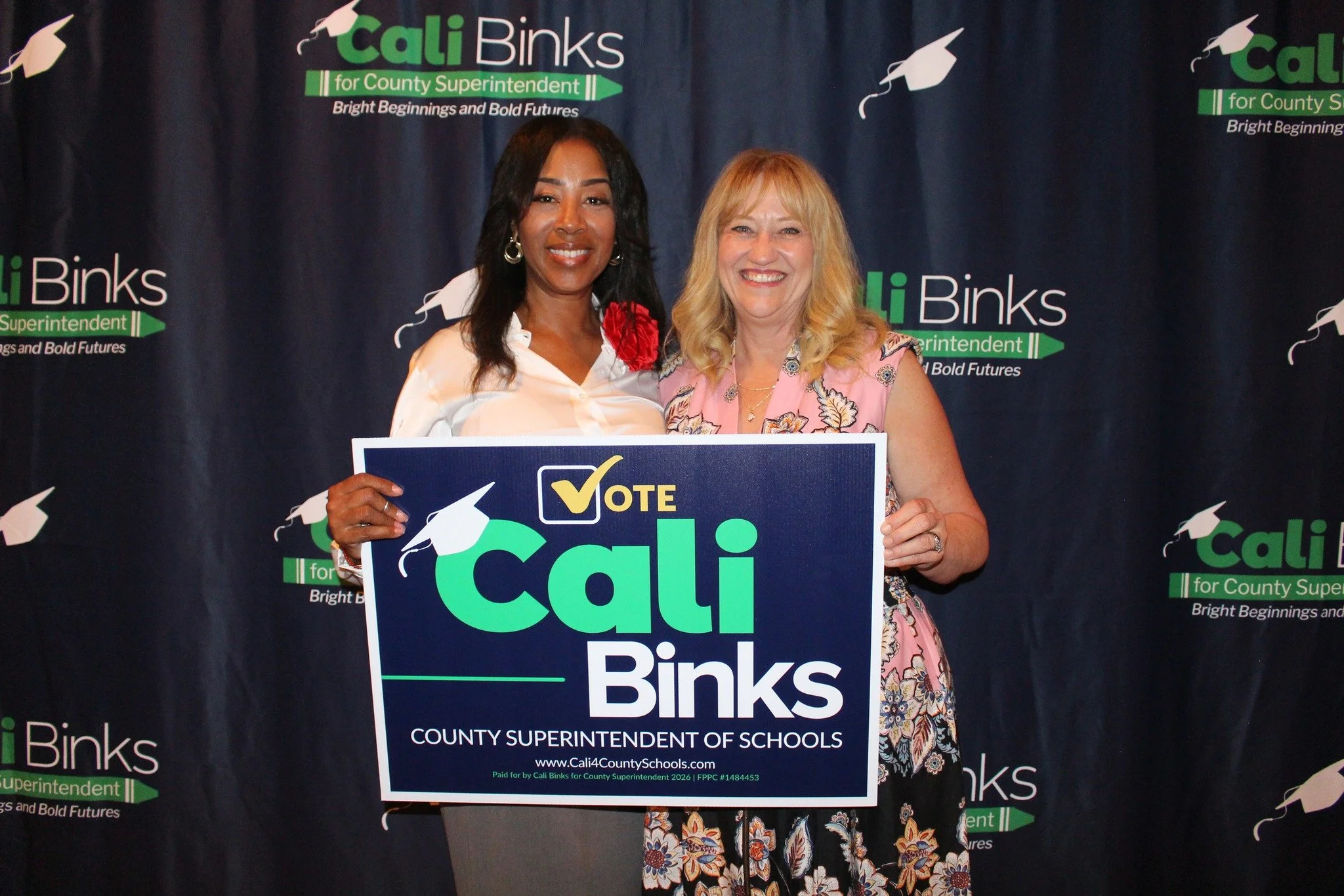 Cali Binks with guest holding a yard sign promoting her campaign.