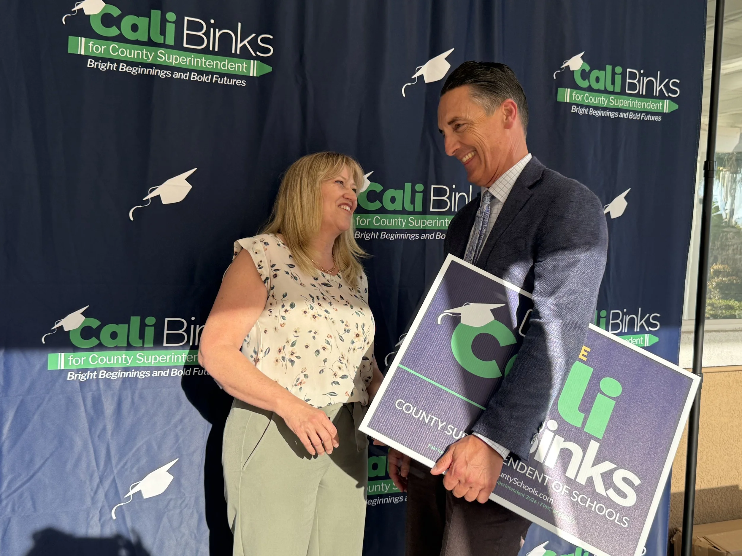 Cali speaking to an adult holding a yard sign