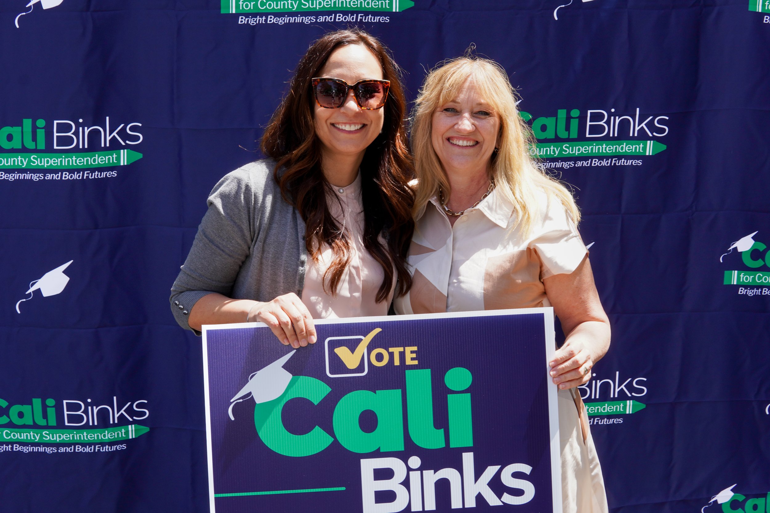 Adult standing next to Cali holding a Cali Binks campaign sign.