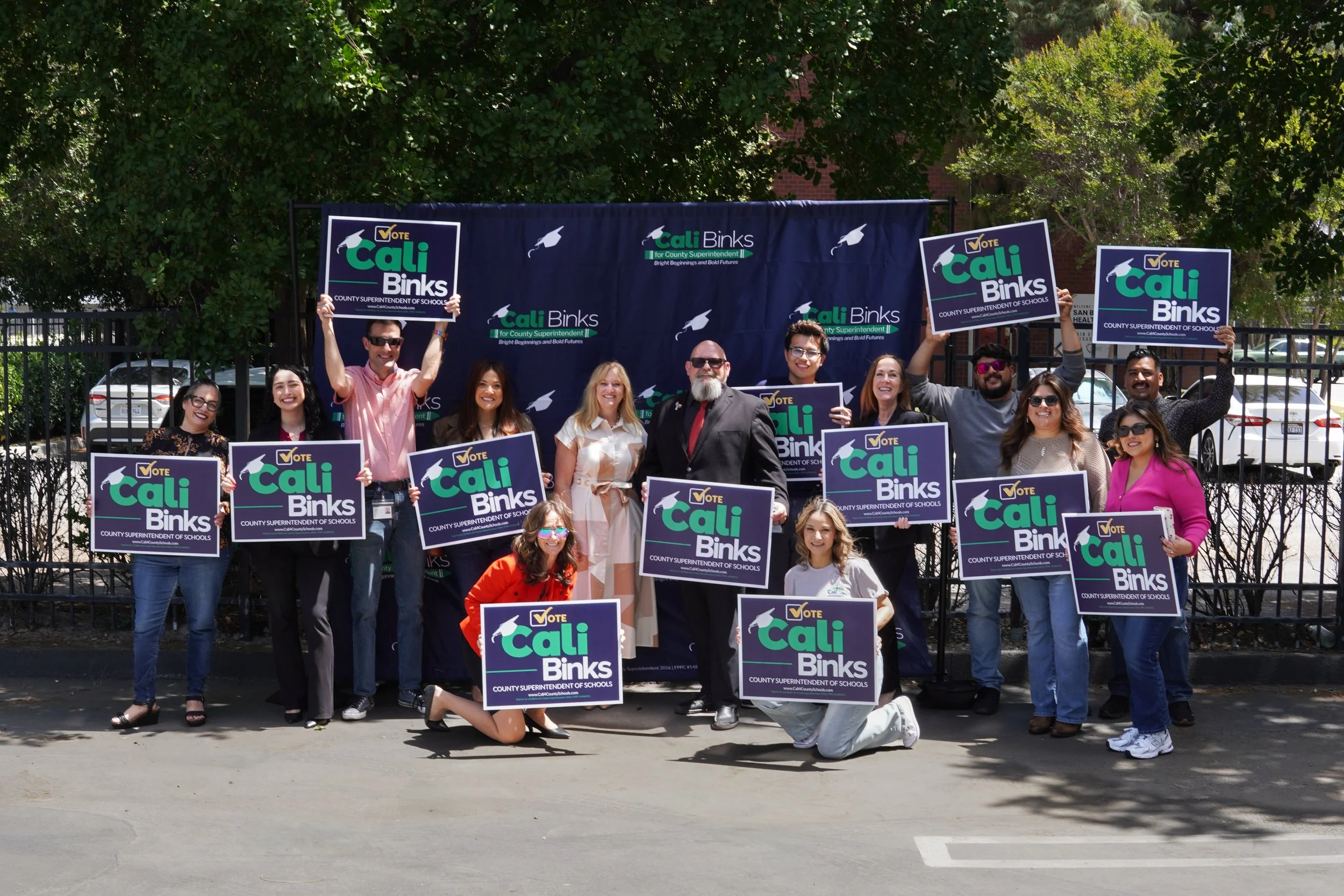 Large group of community members posing with yard signs and Cali Binks in the center.
