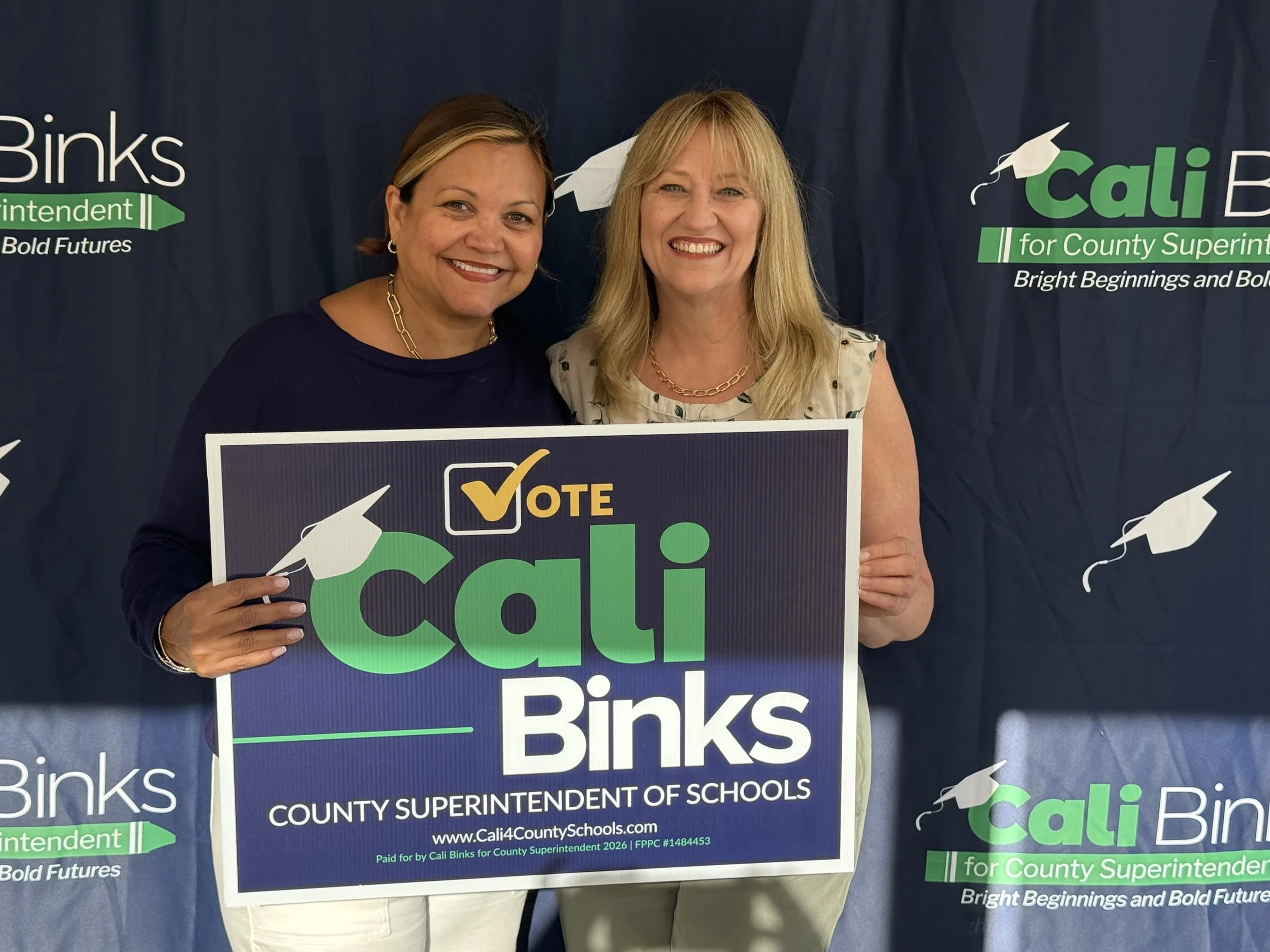Dr. Christina Pierce holding a yard sign with Cali Binks
