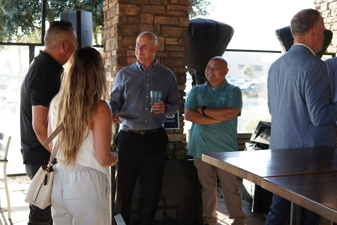 Cali Bink's husband speaking to three event guests.