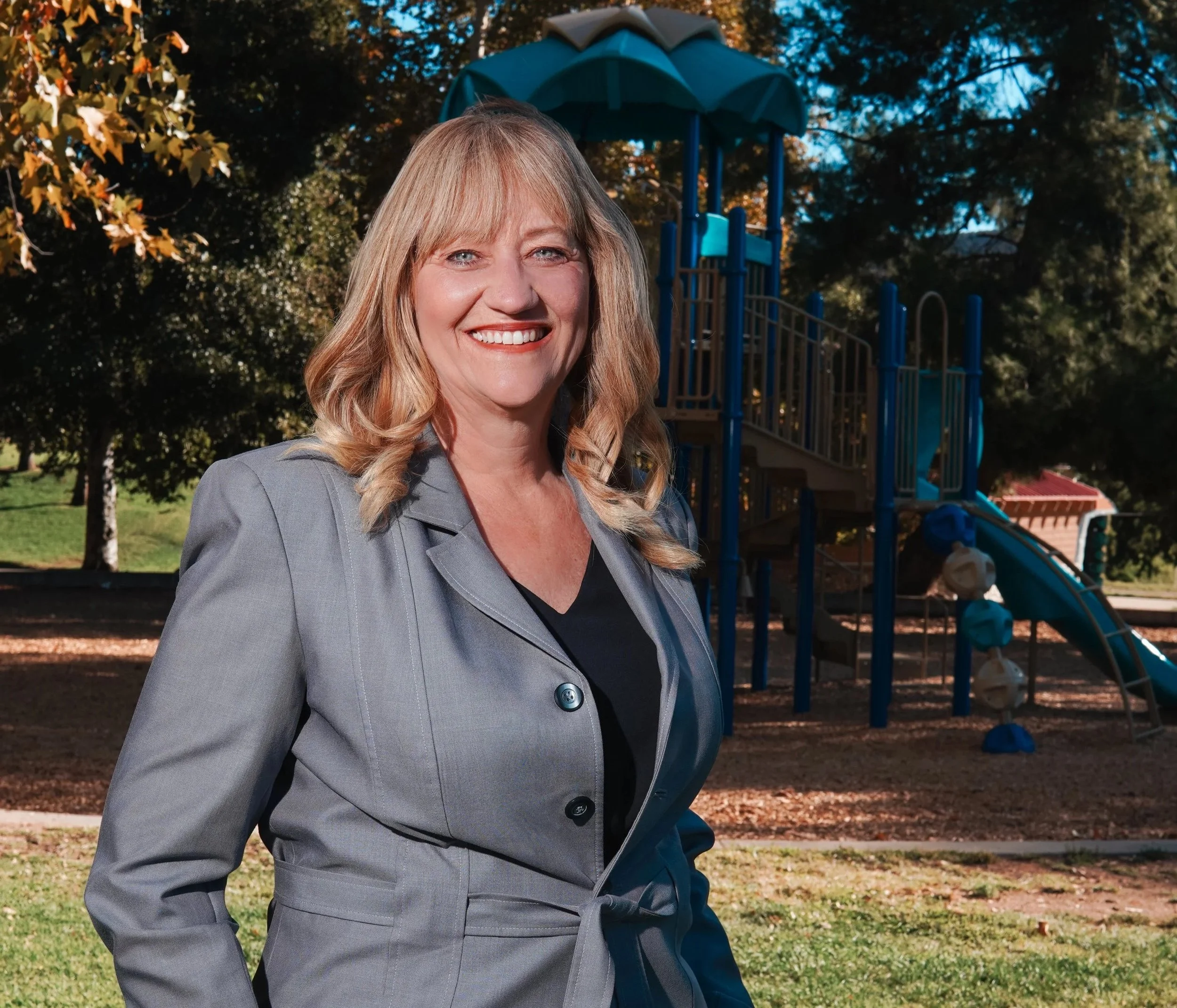 Cali in a suit in front of a playground.