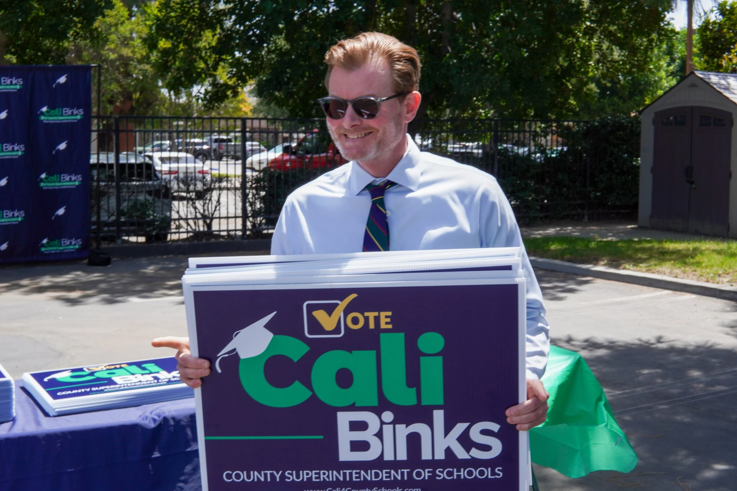 Adult holding several Cali Binks campaign sign.