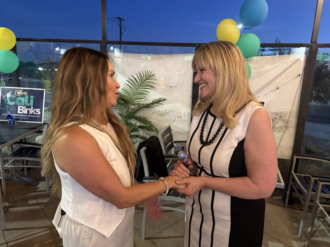 Cali holding hands and speaking to guest.