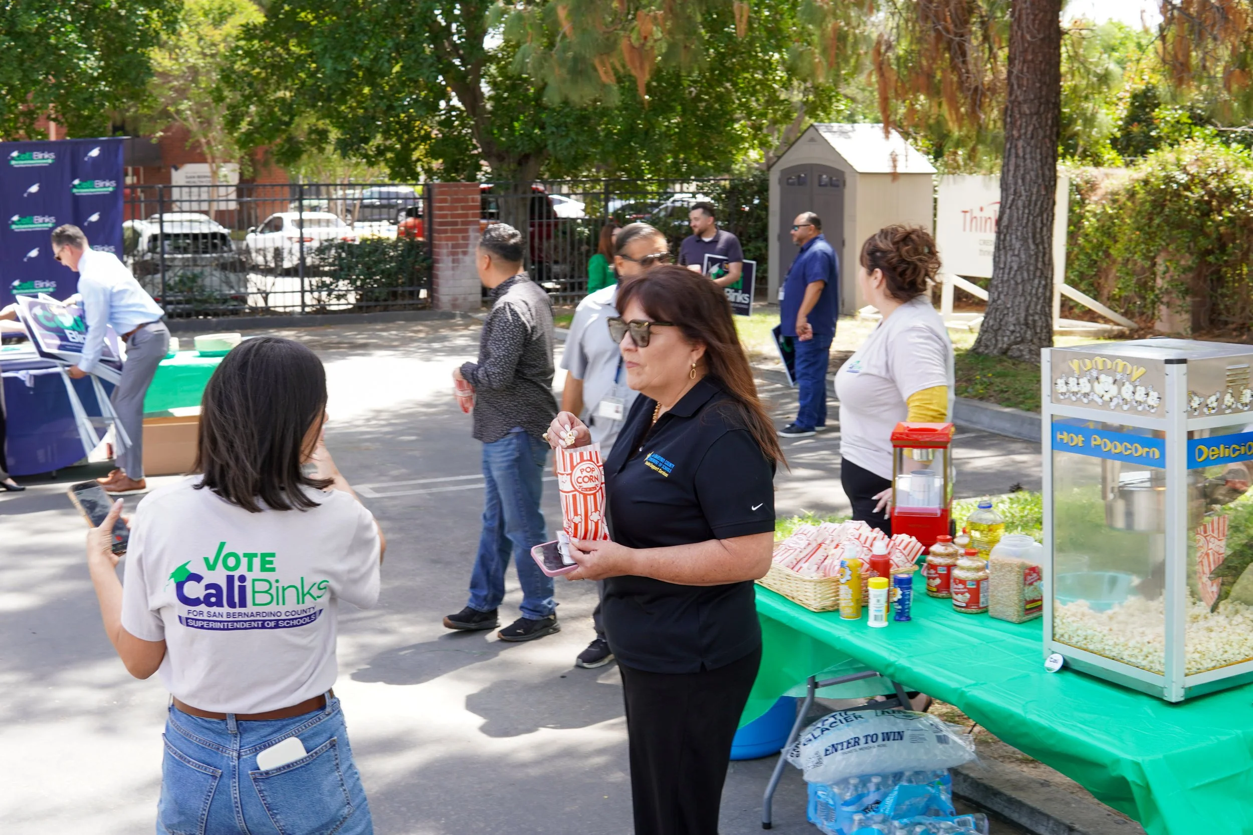 A group of adults networking, eating popcorn, and picking up yard signs.