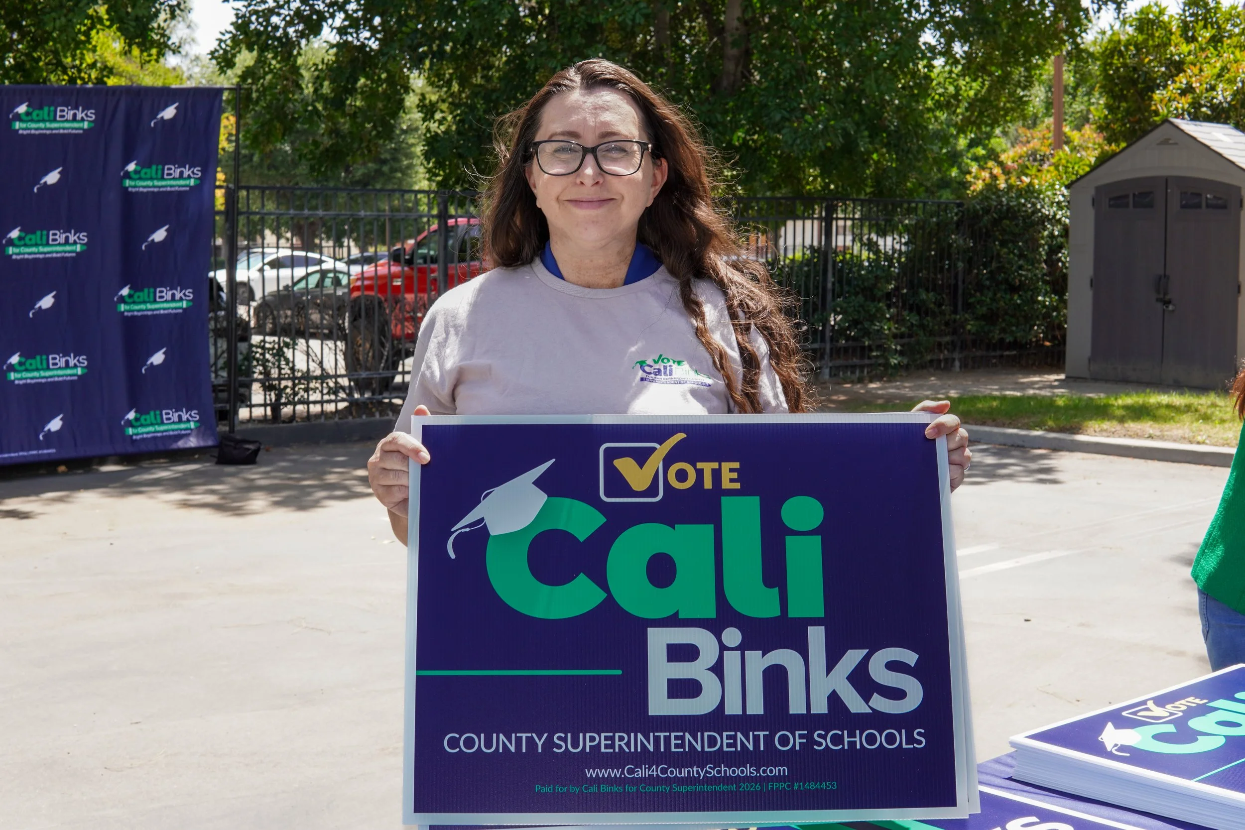 Adult holding a Cali Binks campaign sign.