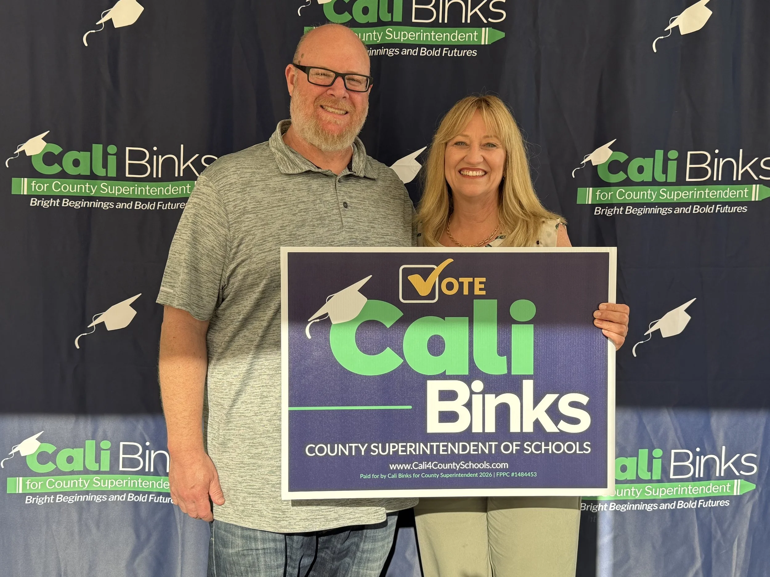 A community member holding a yard sign with Cali