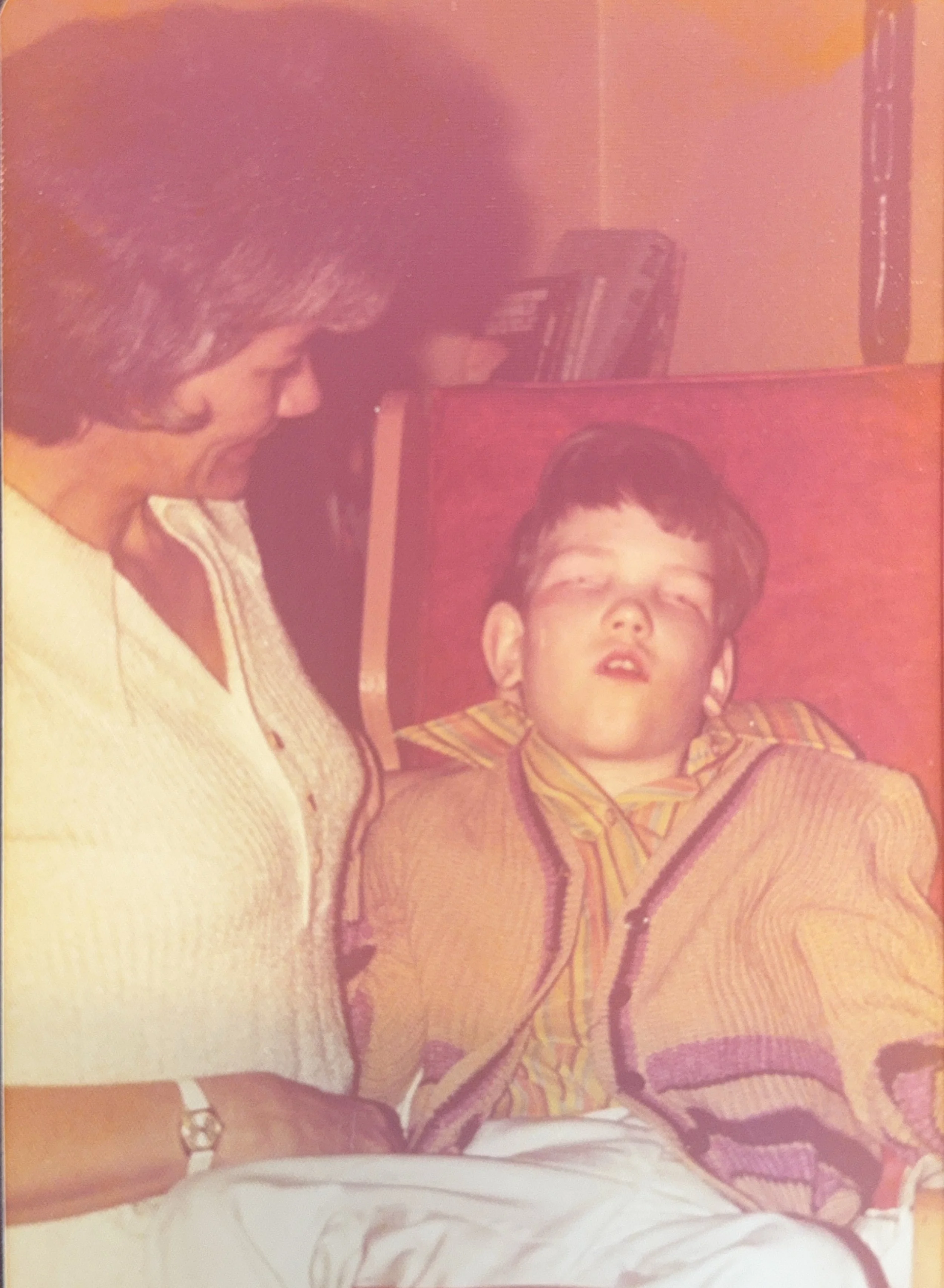 Cali's brother sitting on a chair and a women next to him.