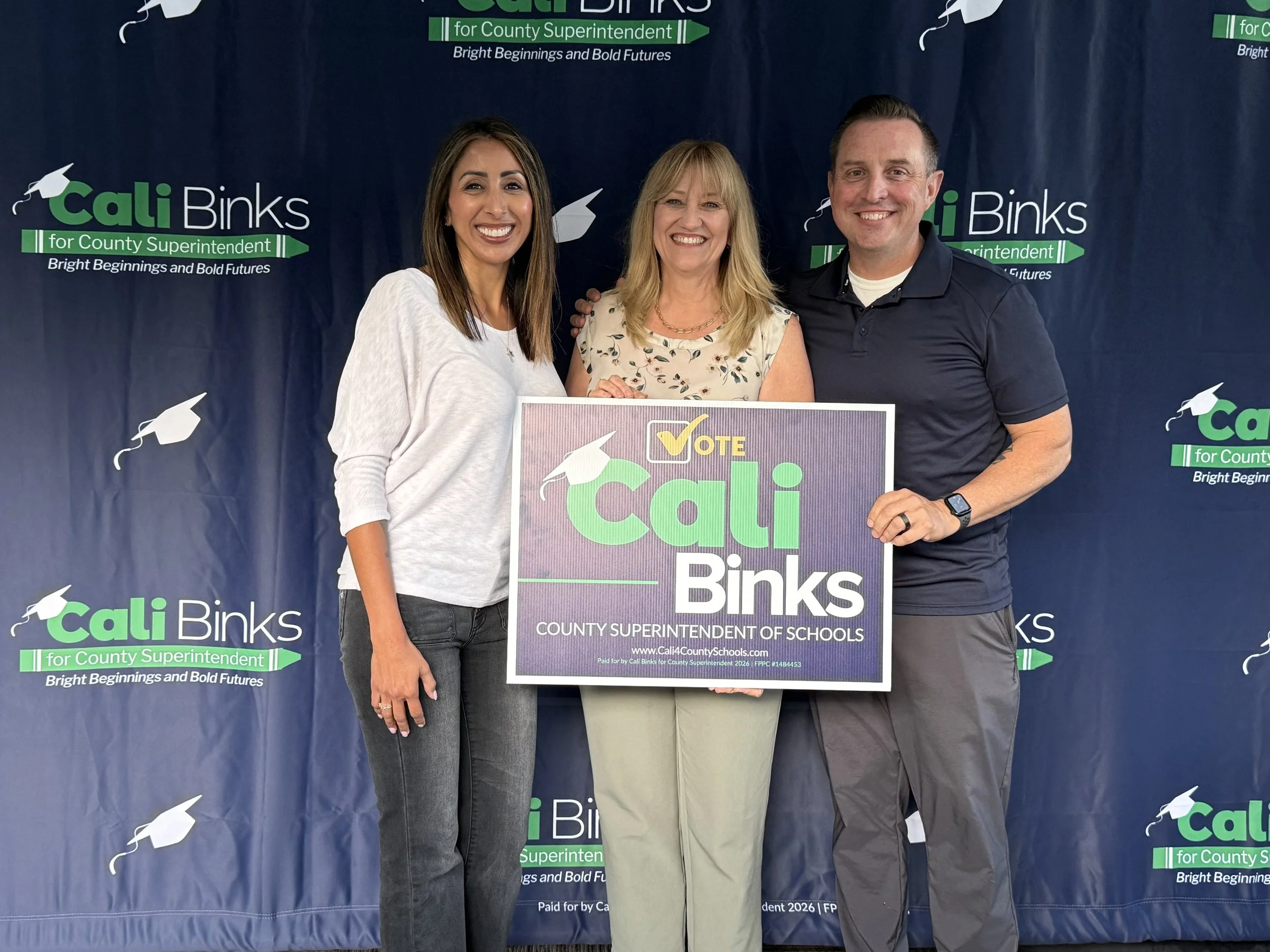 Cali with two community members holding a yard sign