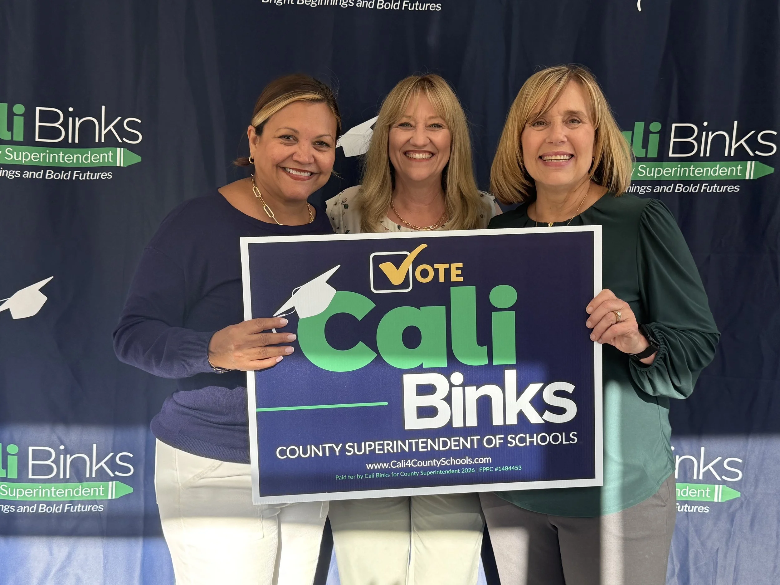 Dr. Christina Pierce holding a sign with Cali Binks and a community member