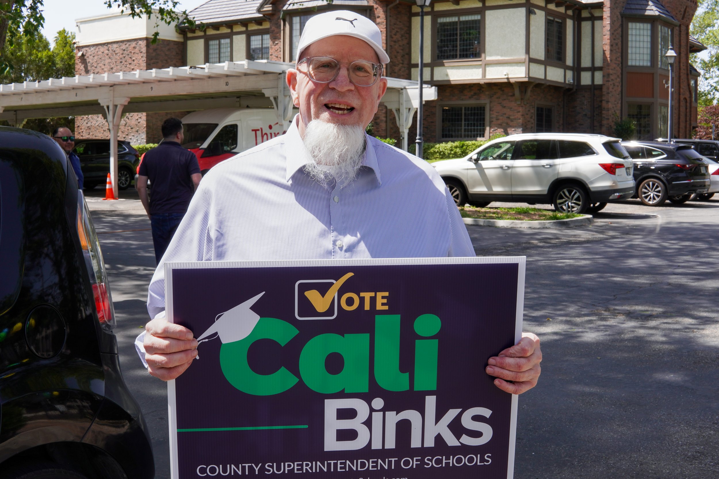 Adult holding a Cali Binks campaign sign.