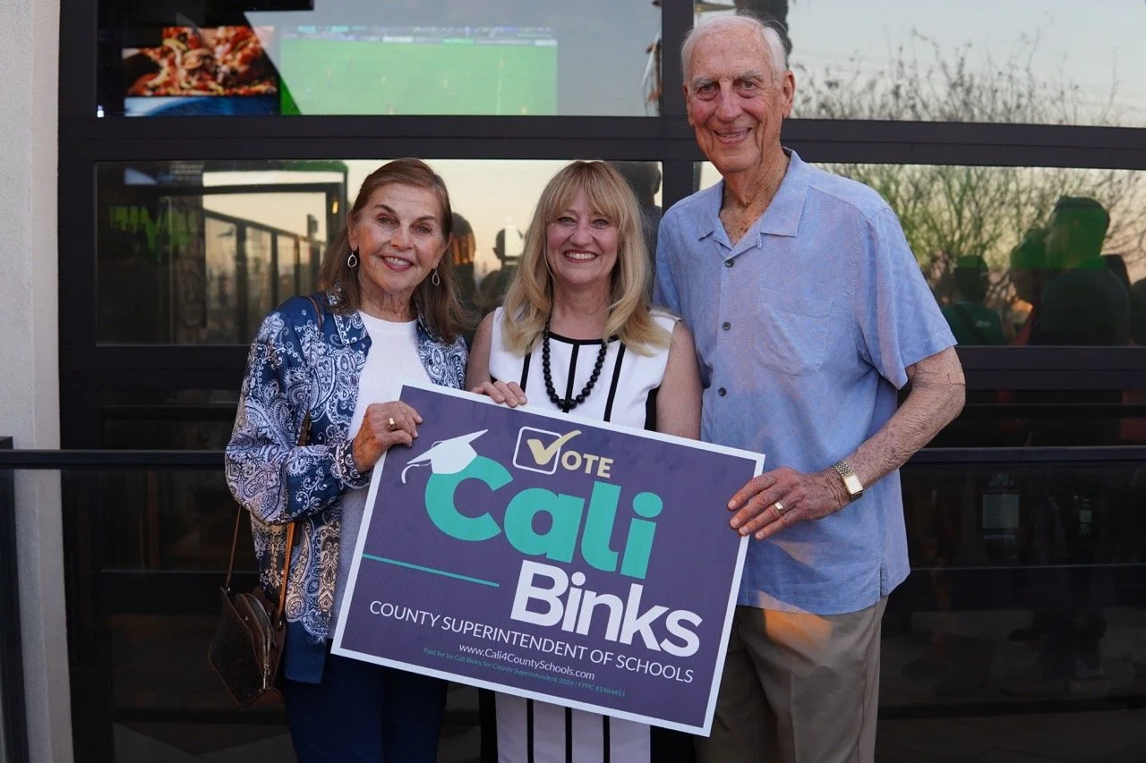 Cali posing with Dr. Herb Fischer and Dr. Cheryl Fischer with a yard sign.