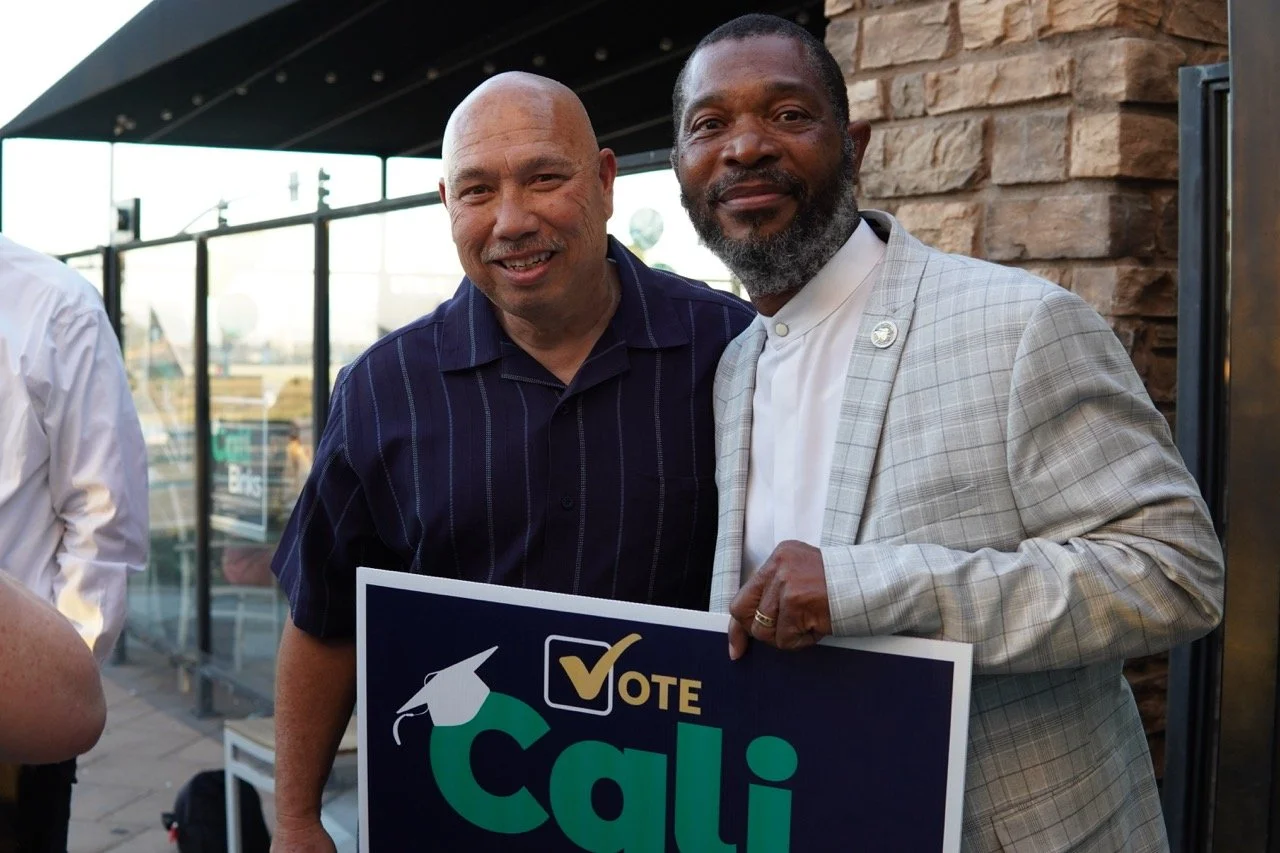Mars Serna, Fontana Unified School District Board Member posing with a guest and holding a yard sign.