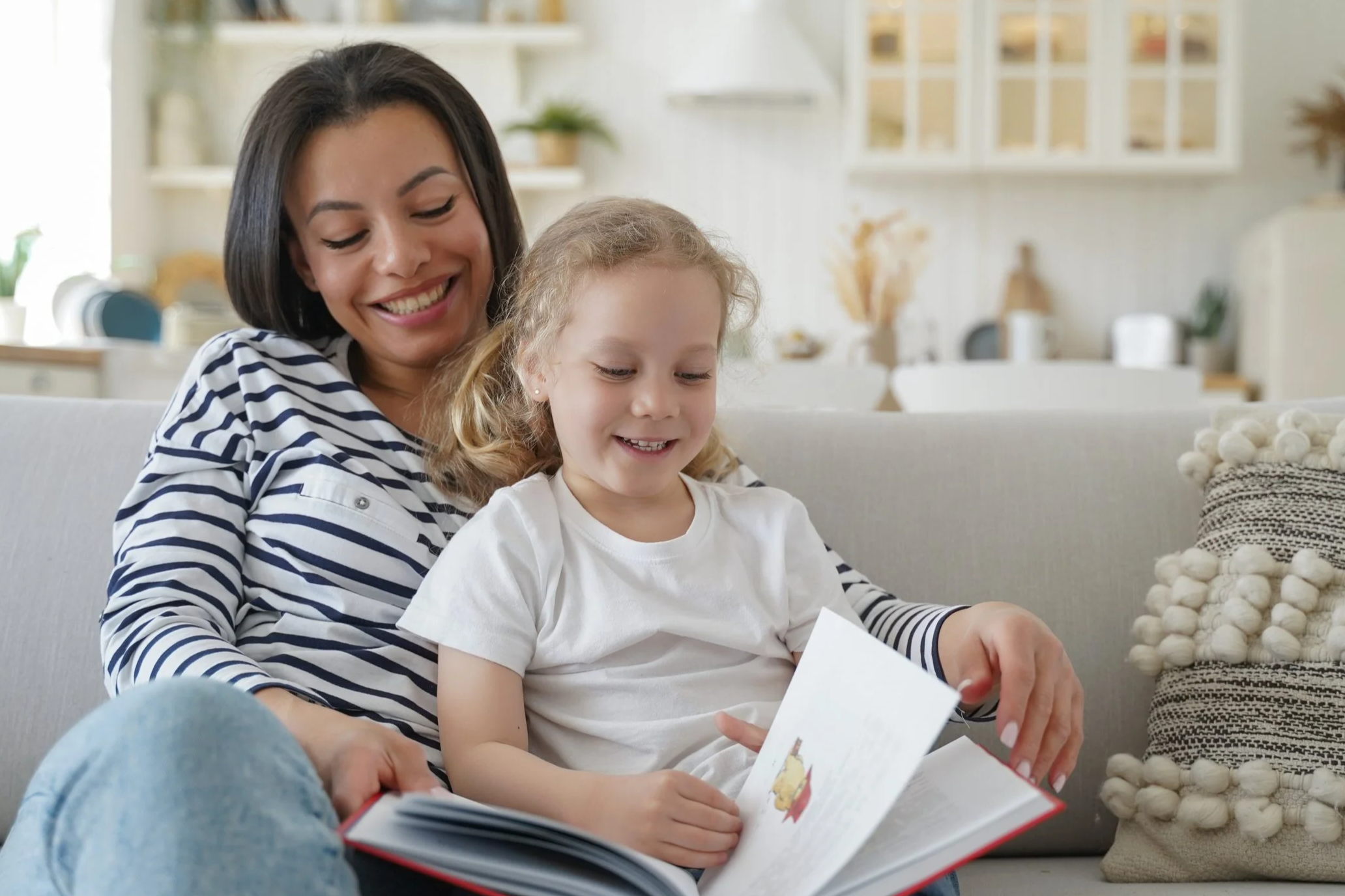 Elementary student reading a book while sitting next to a parent.