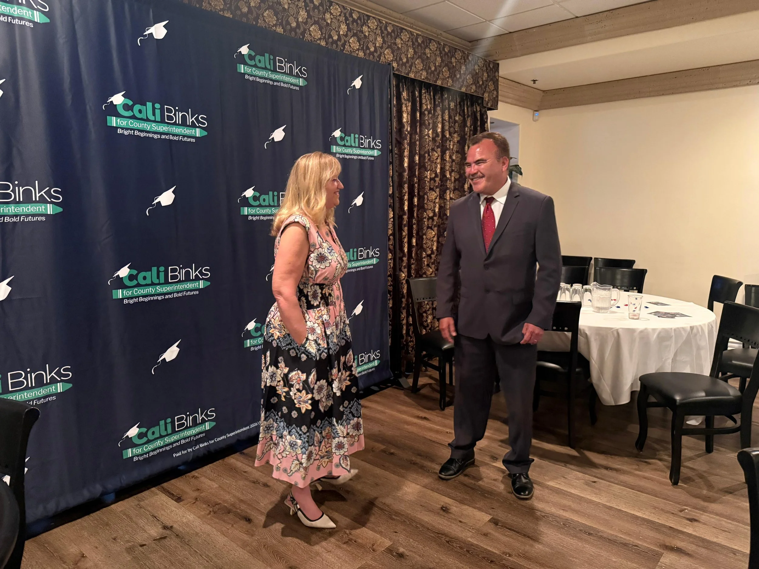 Cali Binks talking with Ted Alejandre while they both smile at the fundraiser.