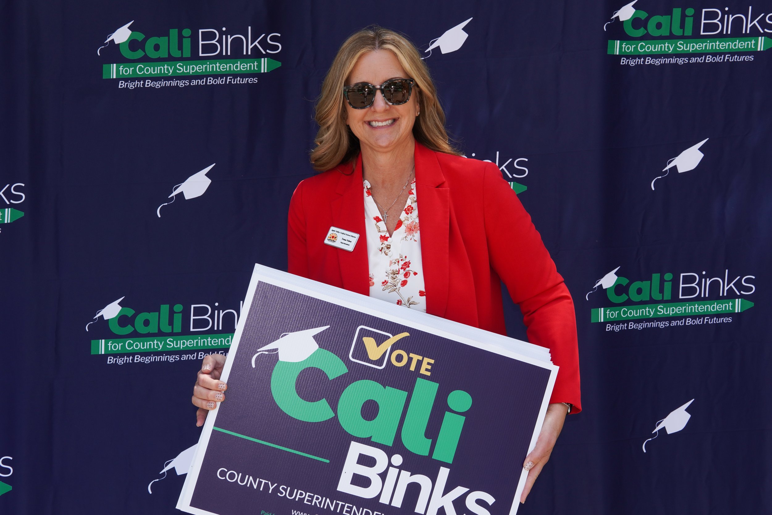 Adult holding a Cali Binks campaign sign.