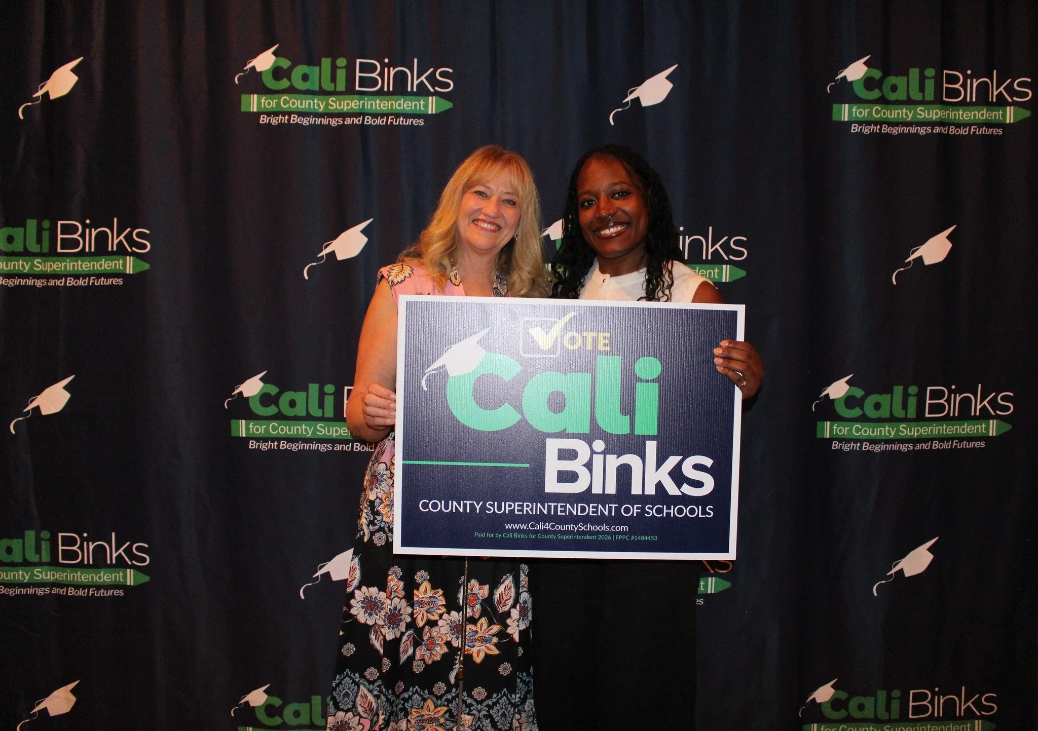Cali Binks with guest holding a yard sign promoting her campaign.