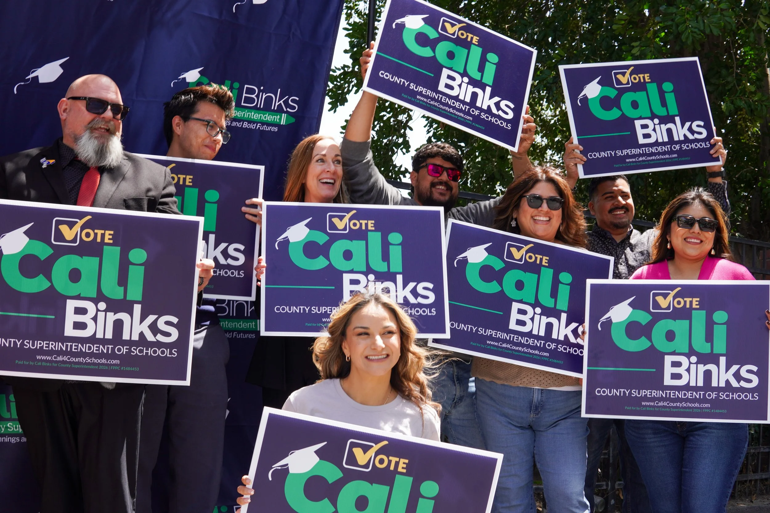 Large group of community members posing with yard signs and Cali Binks in the center.