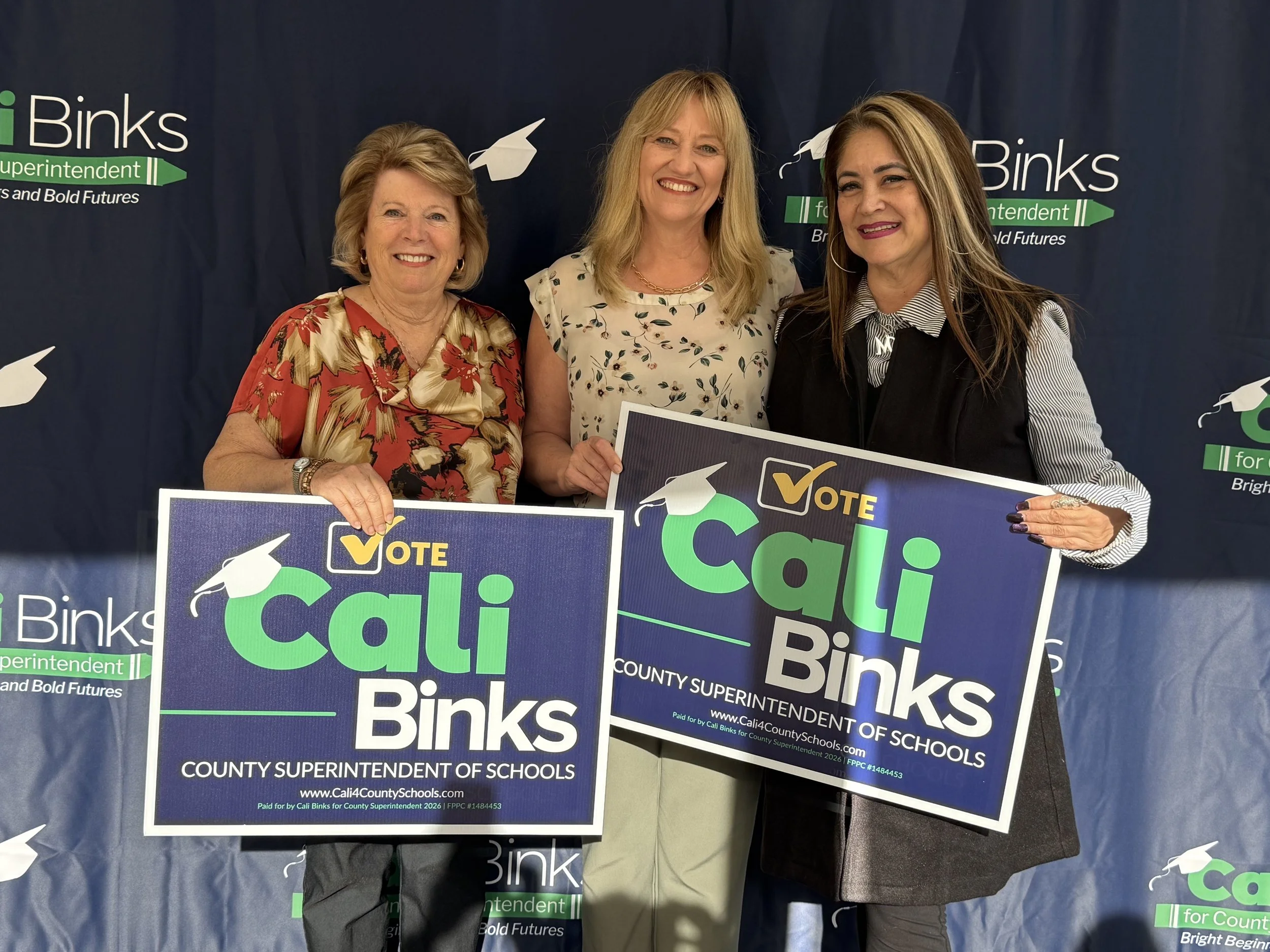 Two community members holding yard signs with Cali
