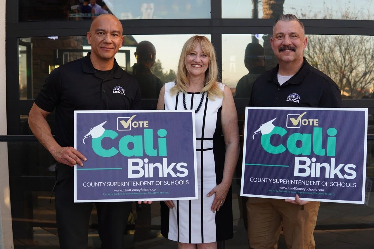Cali Binks posing with two United Probation Officers holding yard signs.