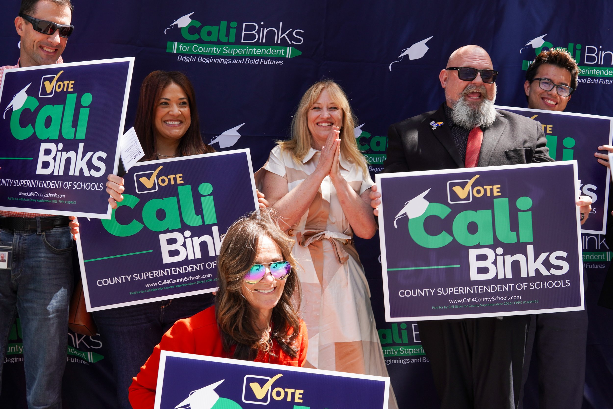 Large group of community members posing with yard signs and Cali Binks in the center.