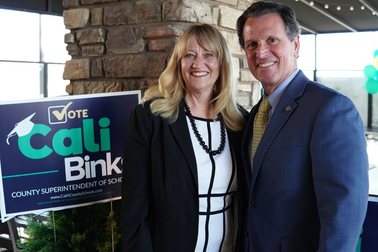 Cali Binks posing with District Attorney Jason Anderson by a campaign yard sign.