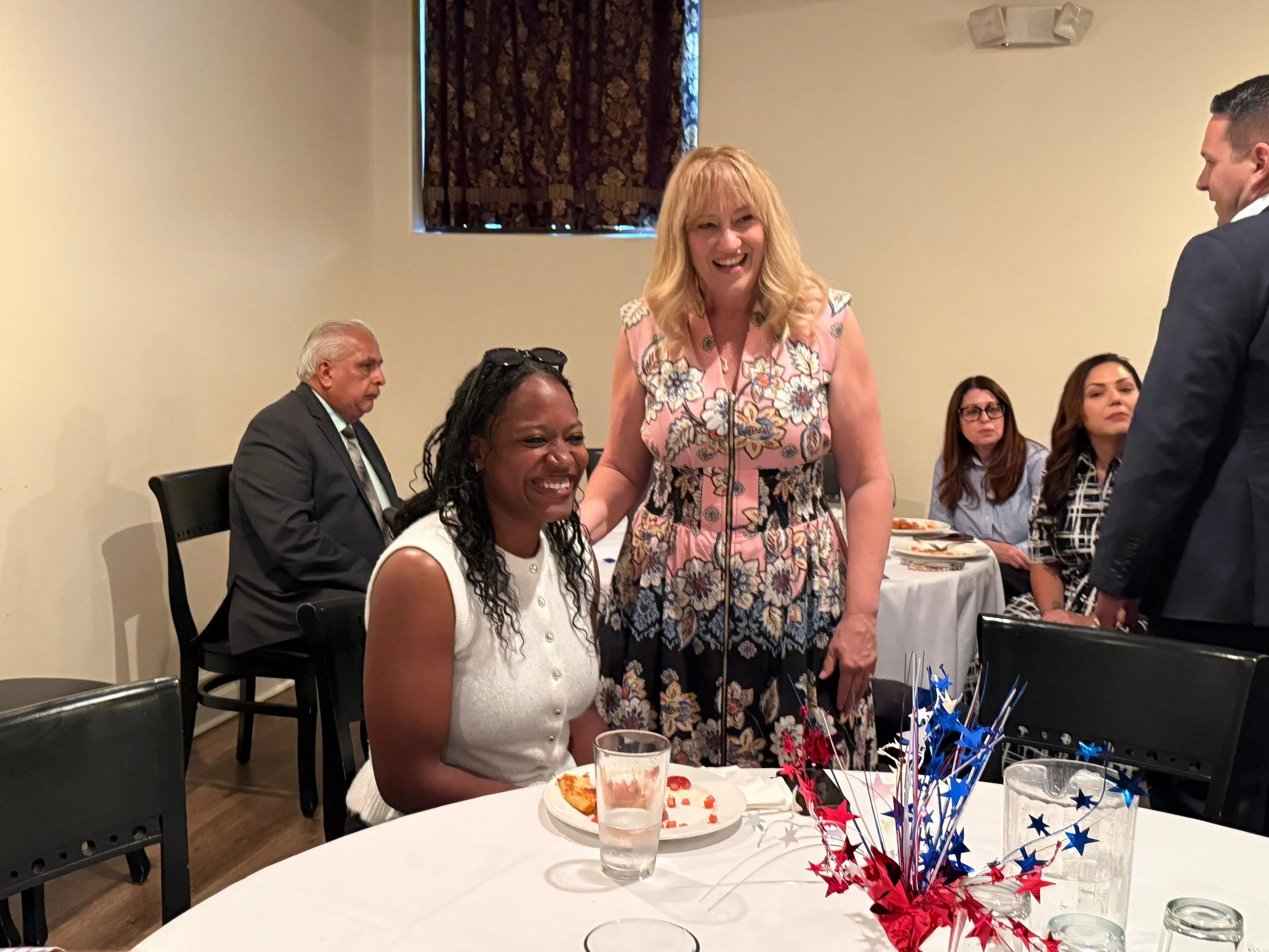 Cali Binks with a guest at the fundraiser and other people in the background sitting at tables.