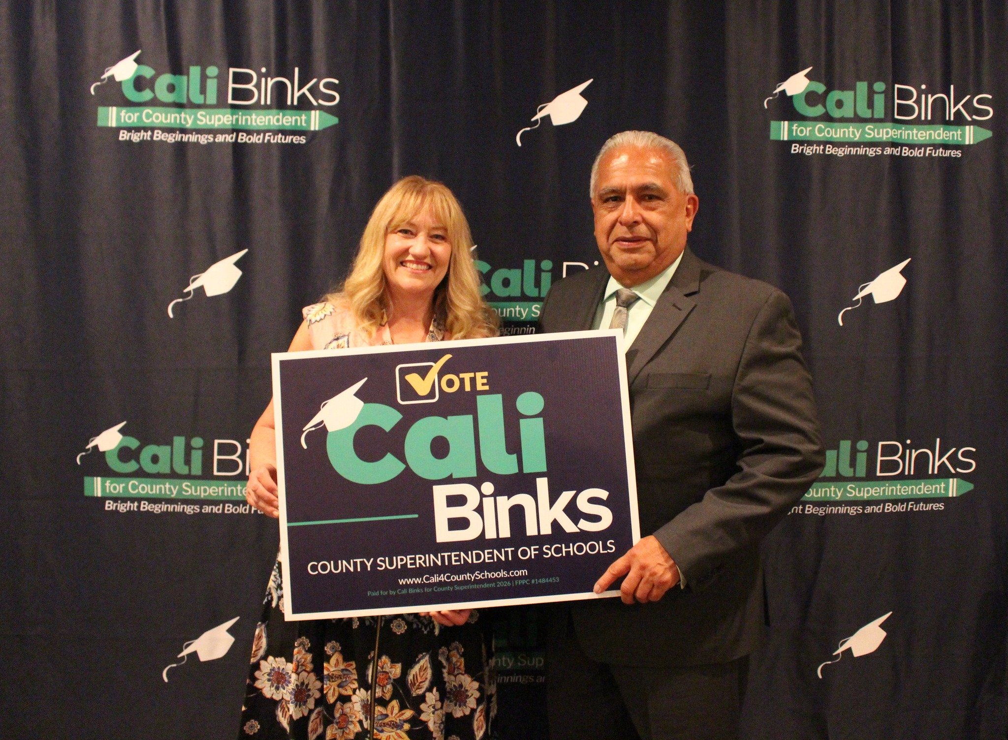 Cali Binks with guest holding a yard sign promoting her campaign.