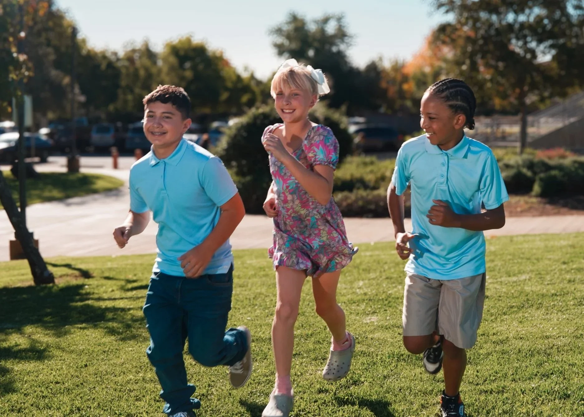 Three students running through the park.