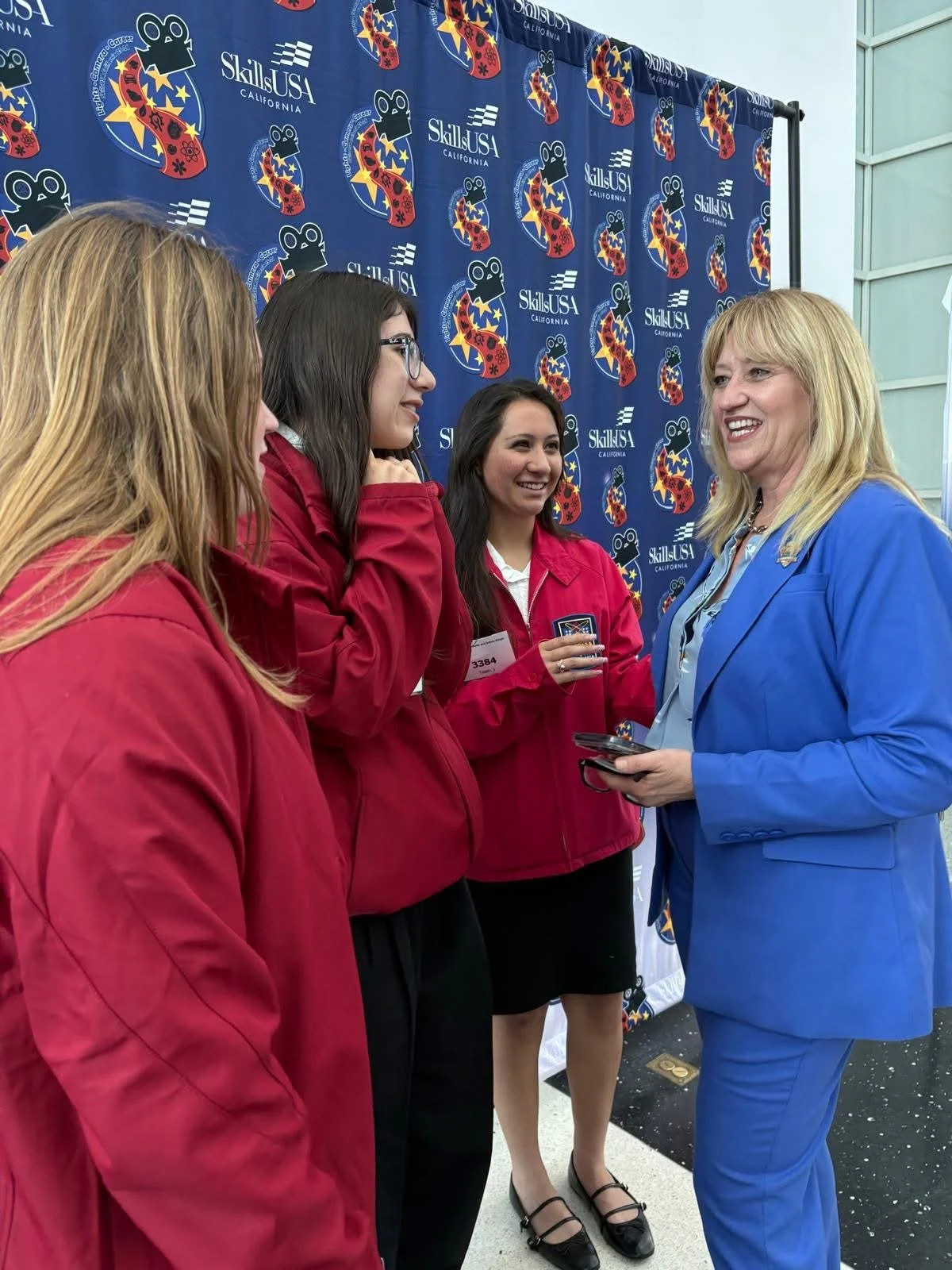 Cali speaking to three high school students as they look at Cali intently and smile.