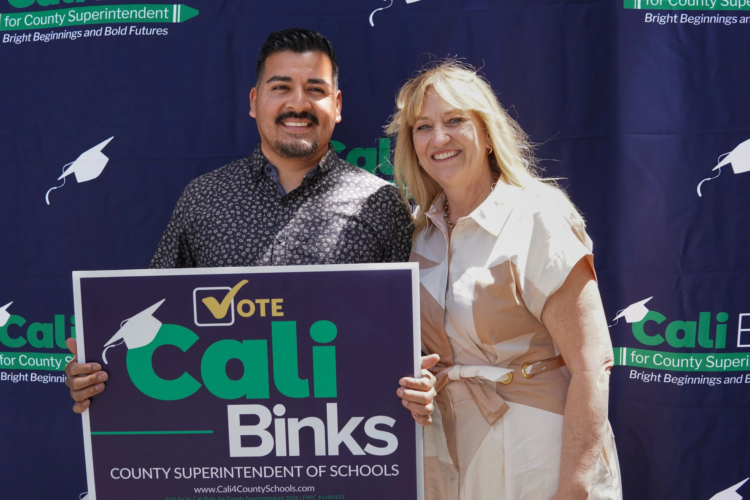 Adult holding a Cali Binks campaign sign and Cali standing next to them.