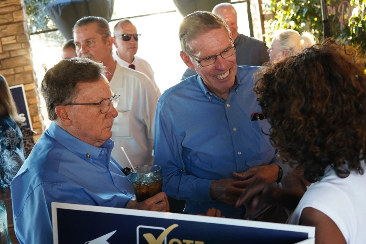 Two event guests speaking to Mayor Acquanetta.