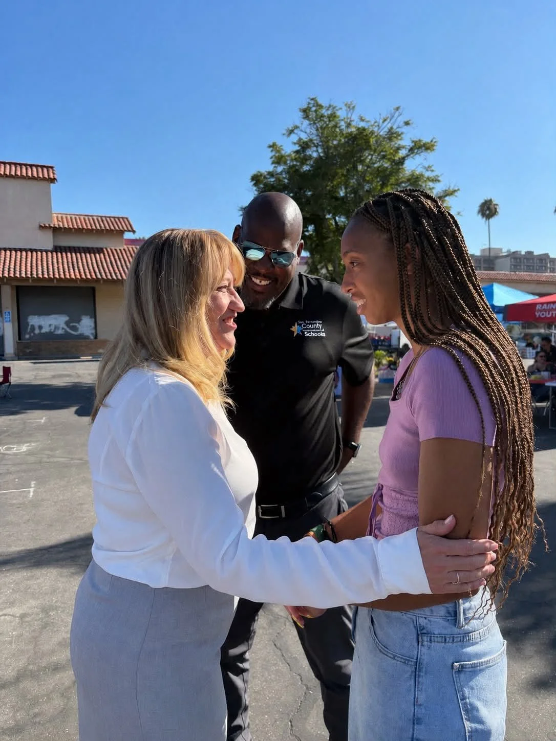 Cali holding a high school student's arm while they speak in front of Dr. Don English also smiling.