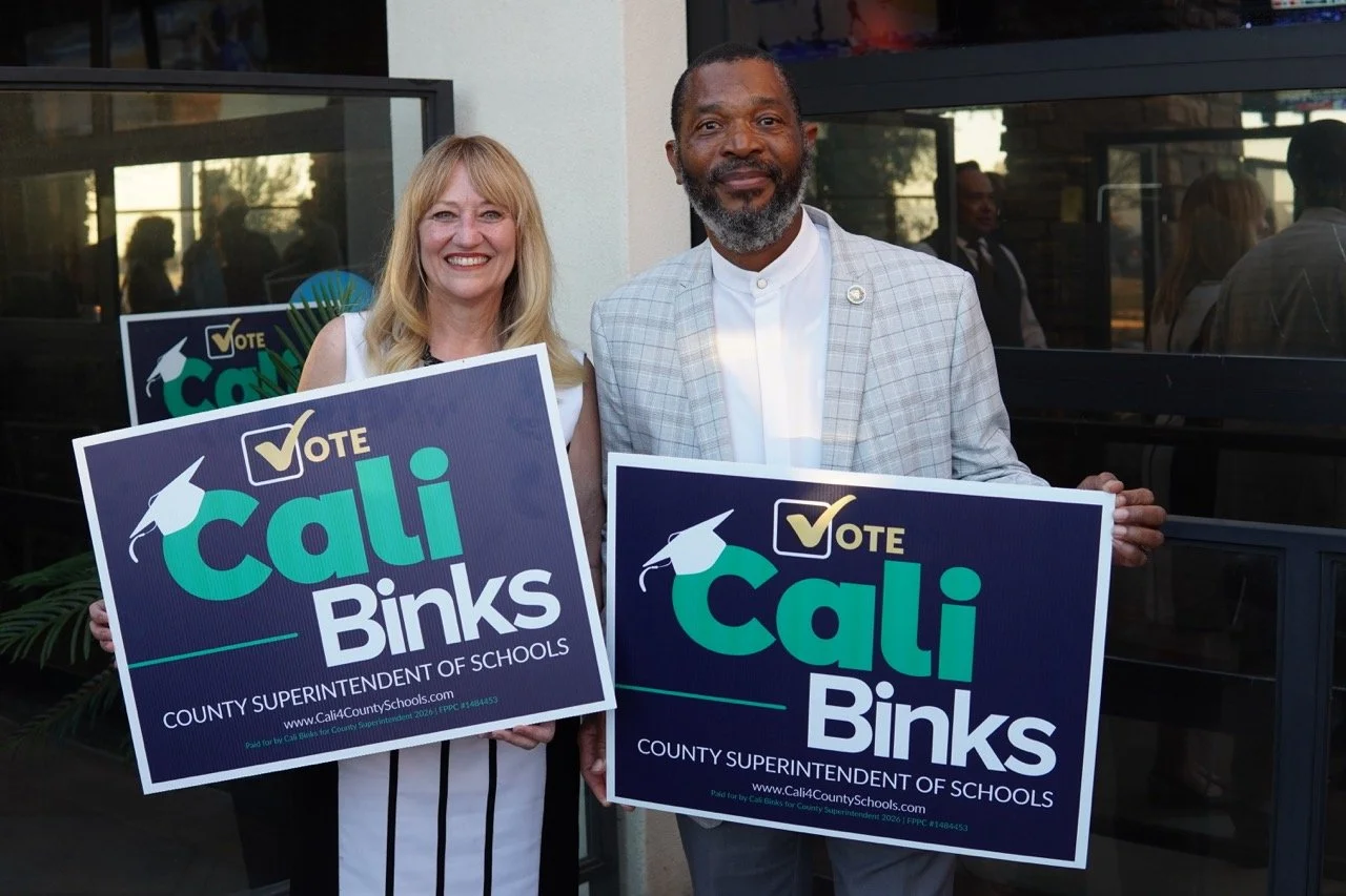 Cali posing with guest holding yard signs.
