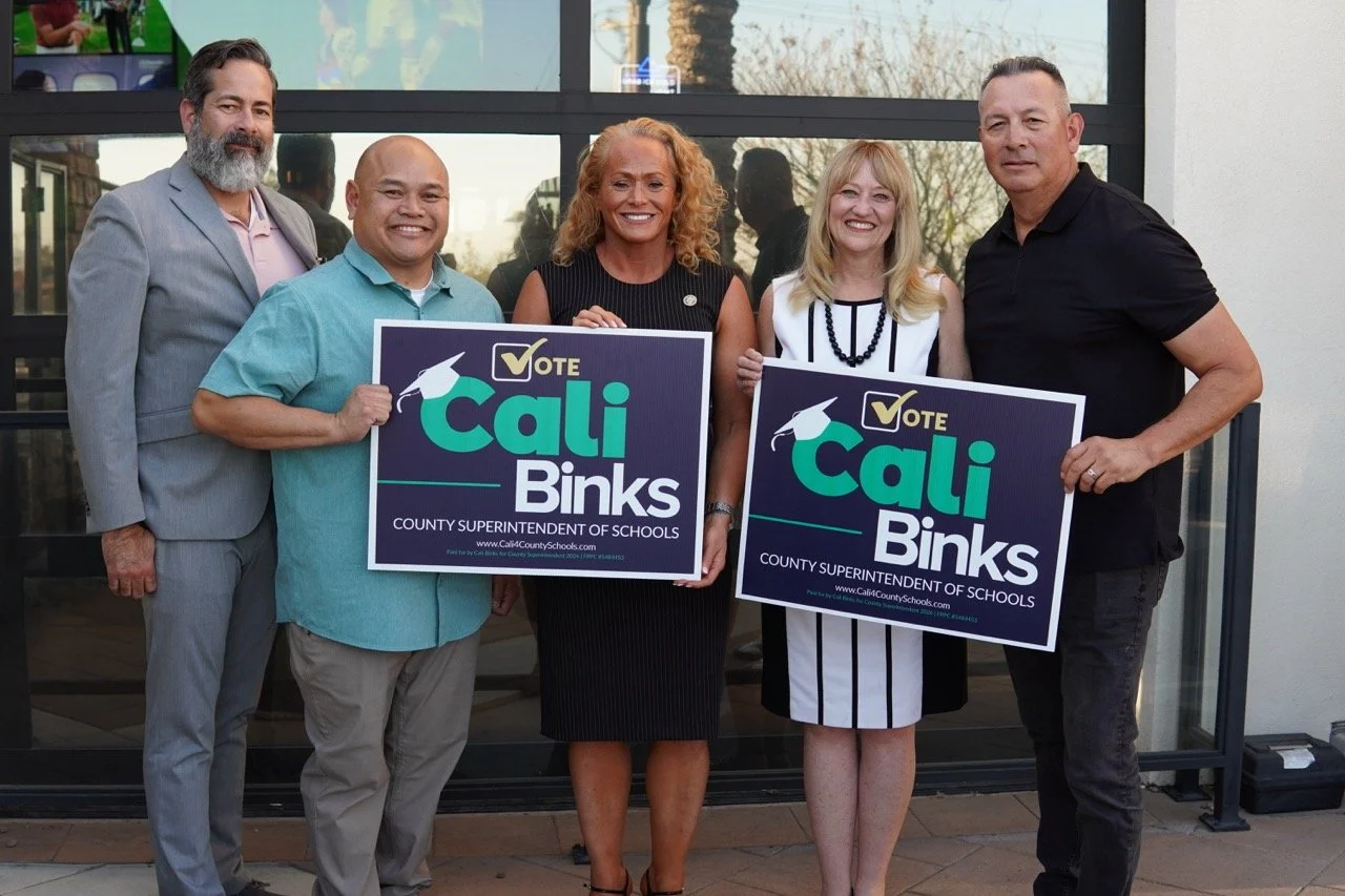 Cali posing with four SEBA members holding yard signs.