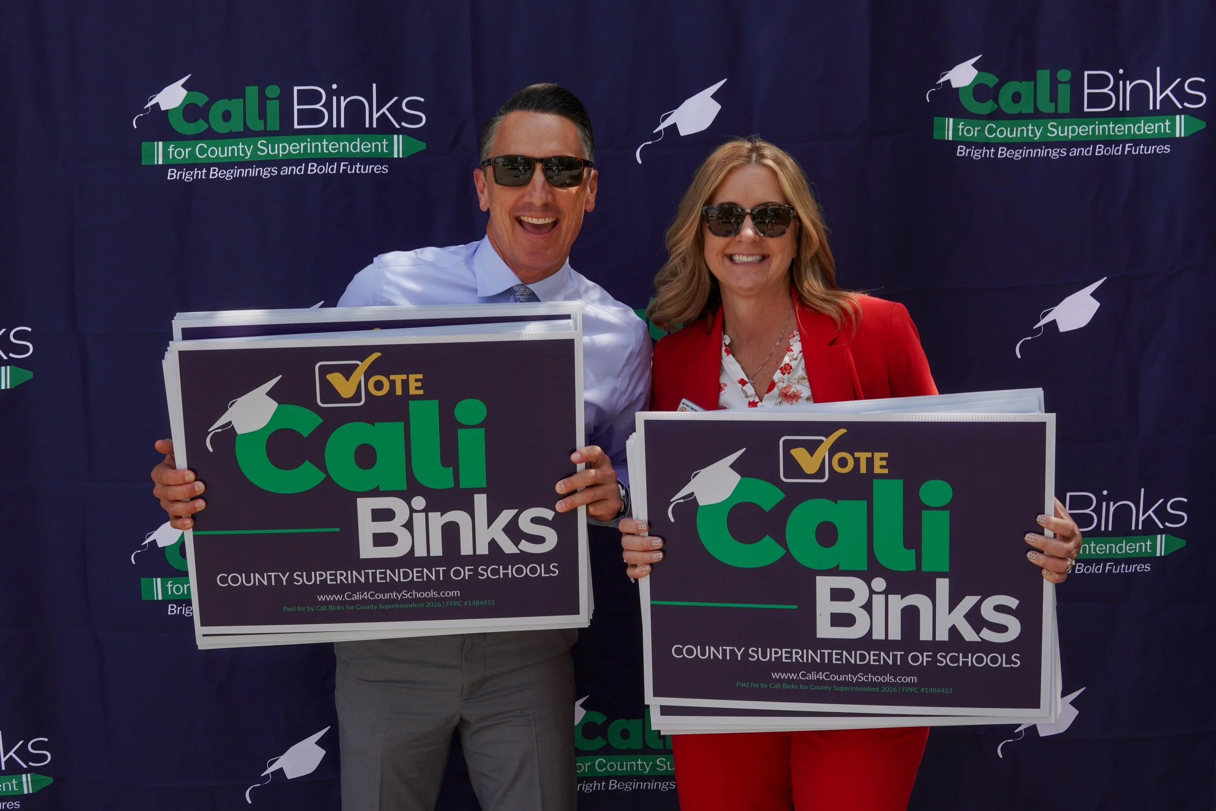 Two adults holding a Cali Binks campaign sign.