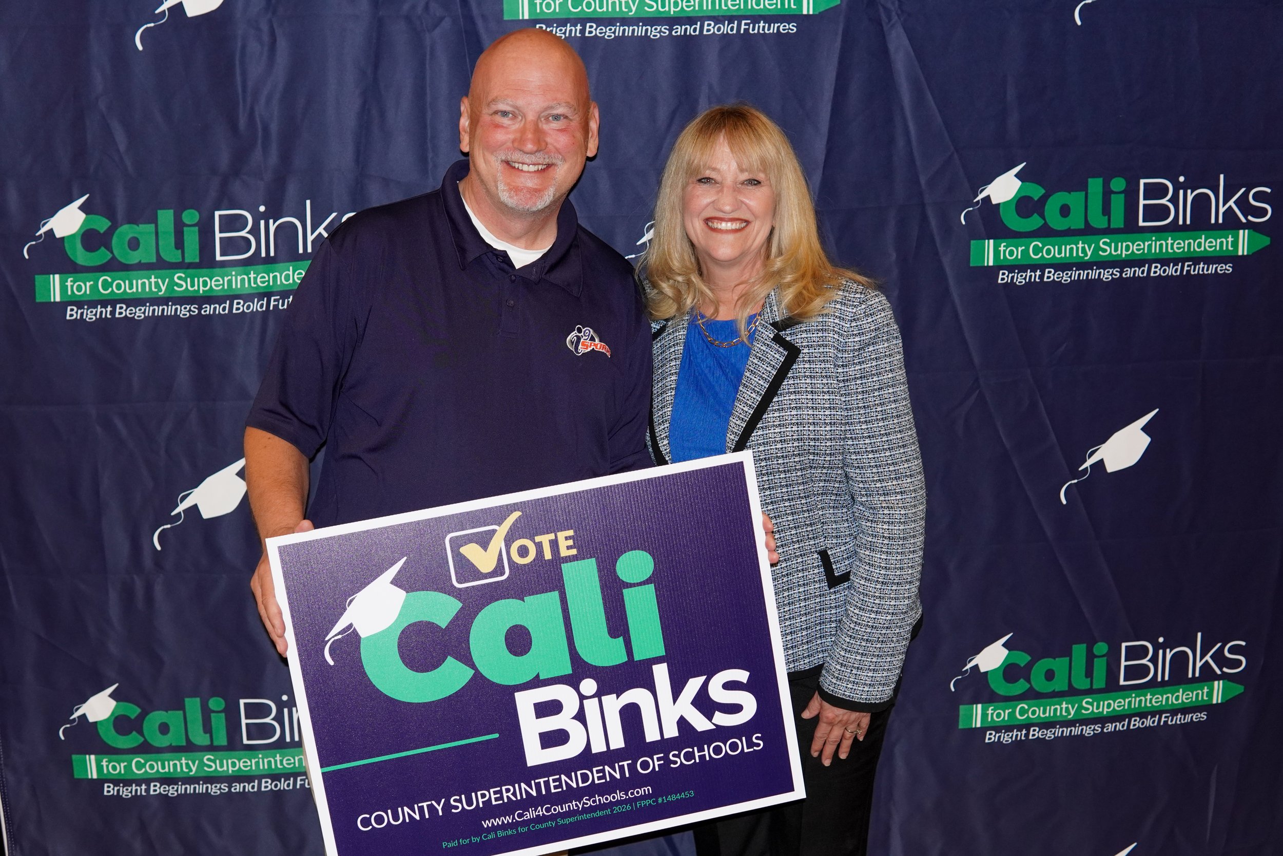 Cali posing for a photo with an adult holding yard sign.