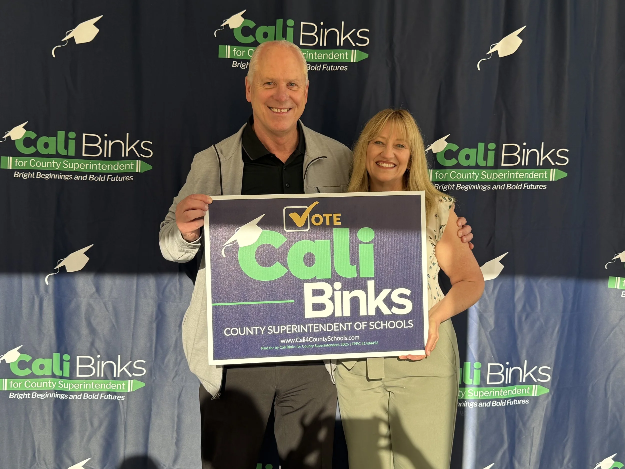 Kelly Binks holding a yard sign with Cali
