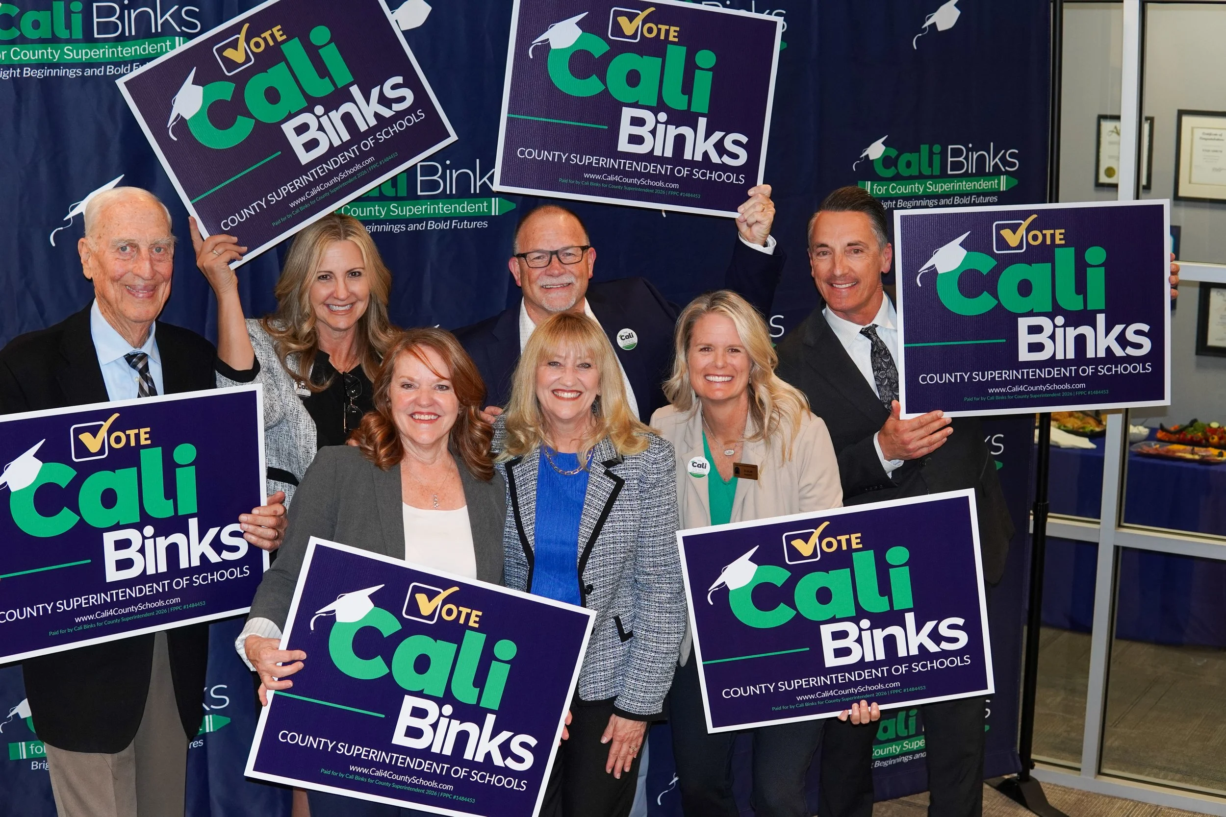 Group of people holding yard signs with Cali Binks in the center