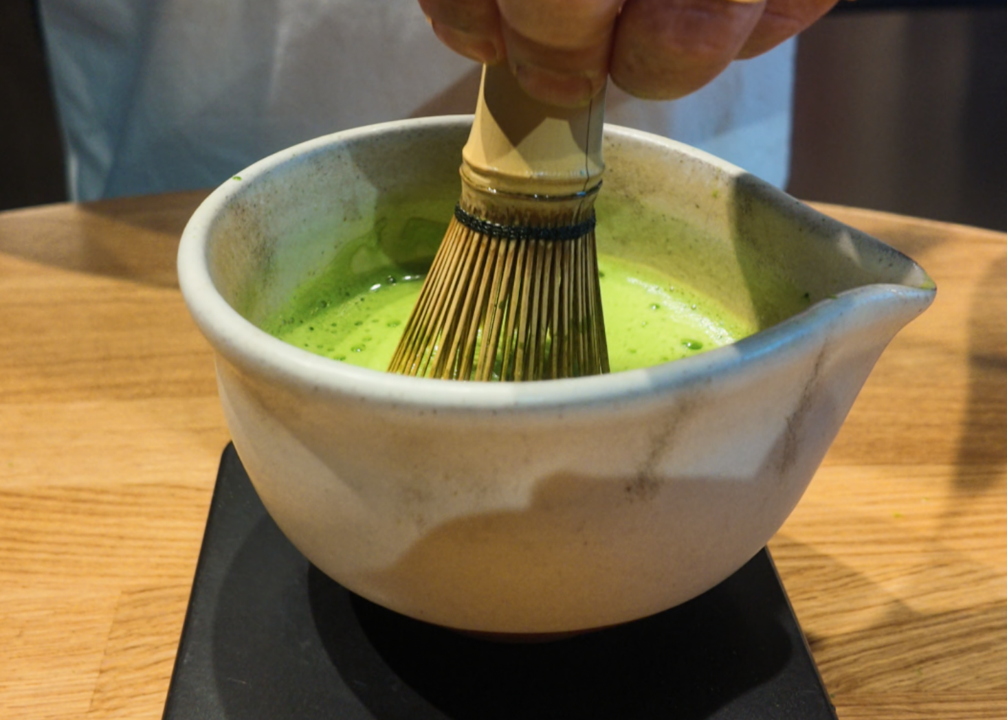 Hand whisking matcha shot (usucha) in a tea bowl