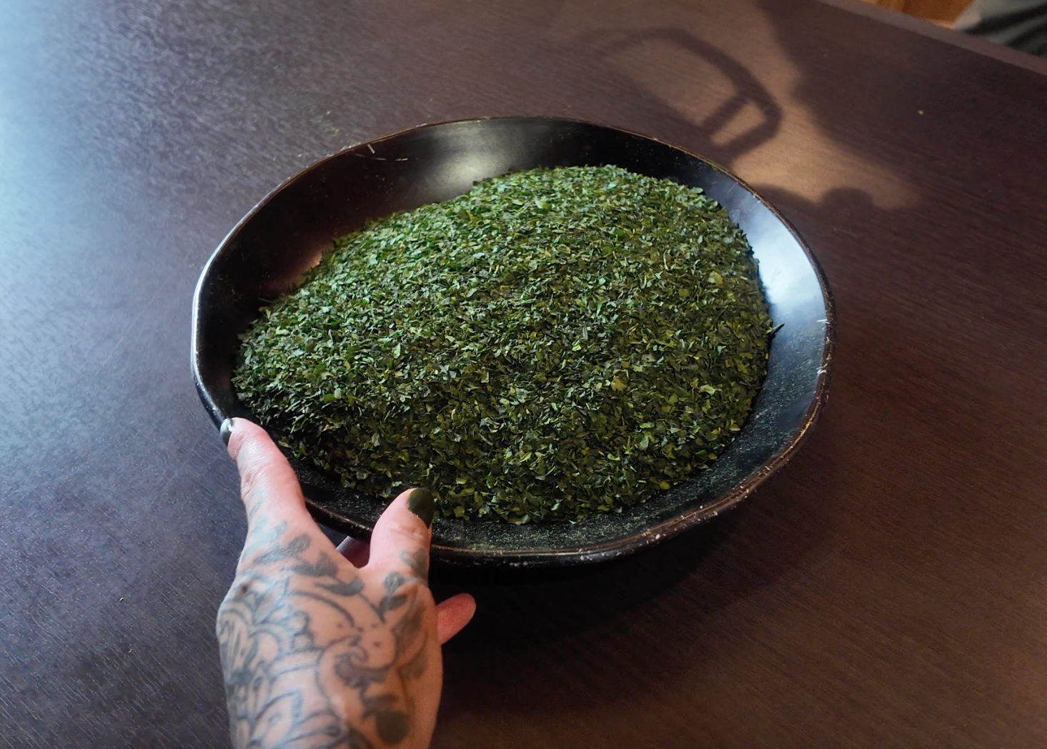 Hand holding a black bowl of tencha leaves