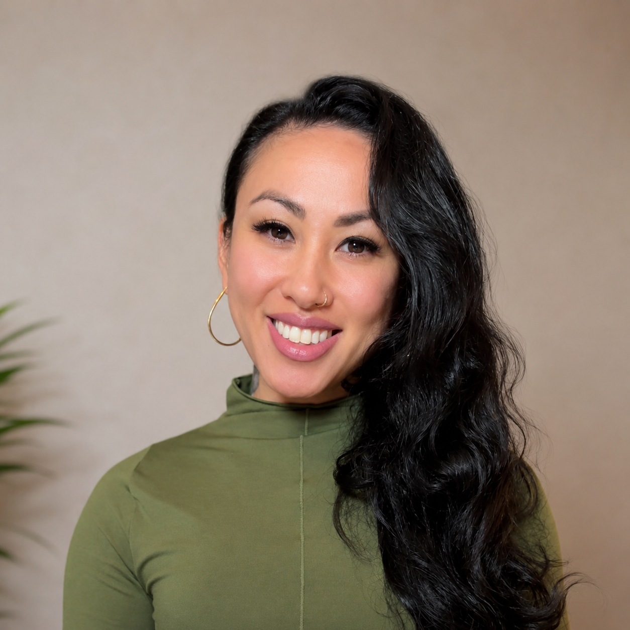 Portrait of Jules smiling with her hair down wearing a green turtleneck