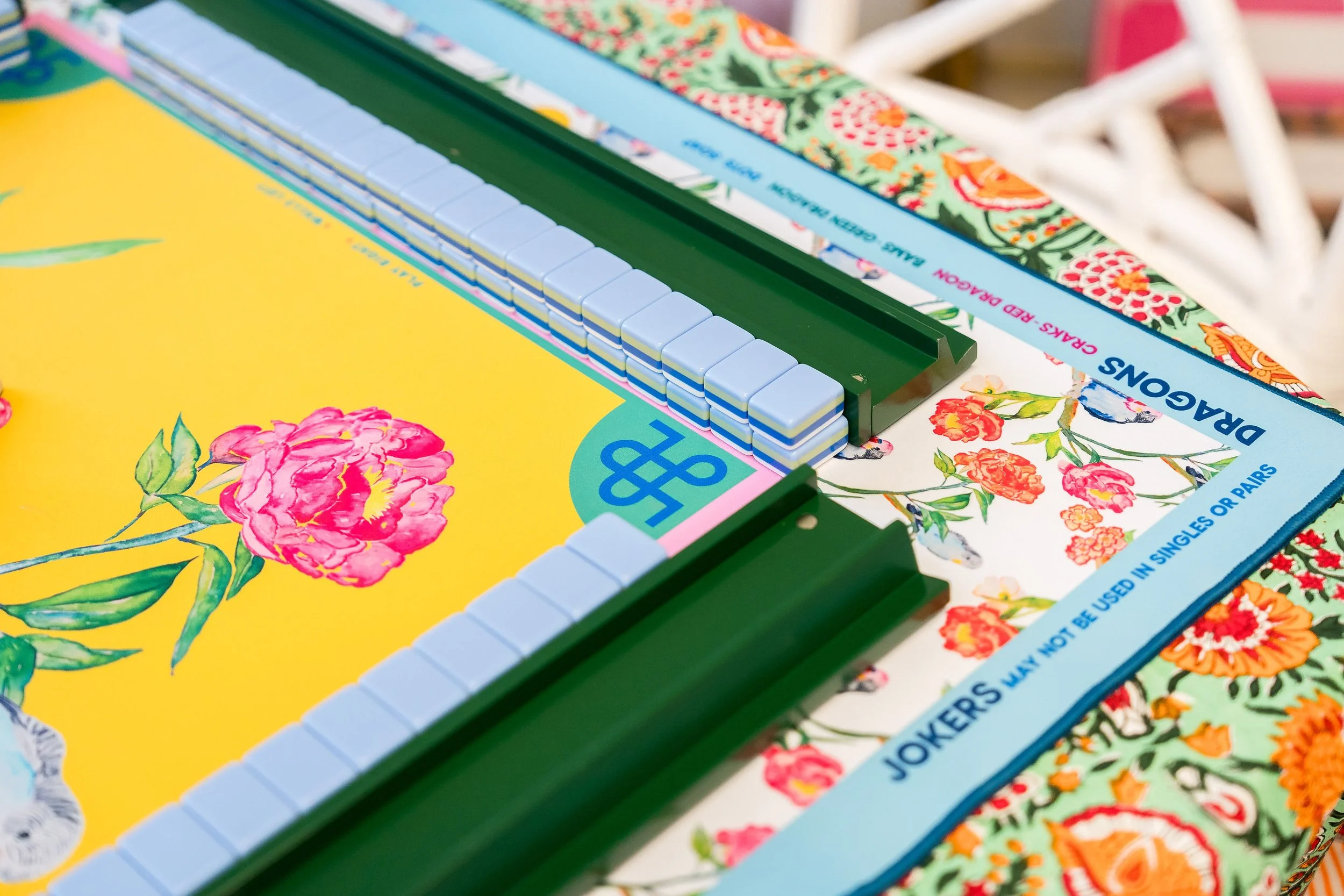 Close-up of a colorful board game with tiles and floral-patterned border, set on a patterned tablecloth.