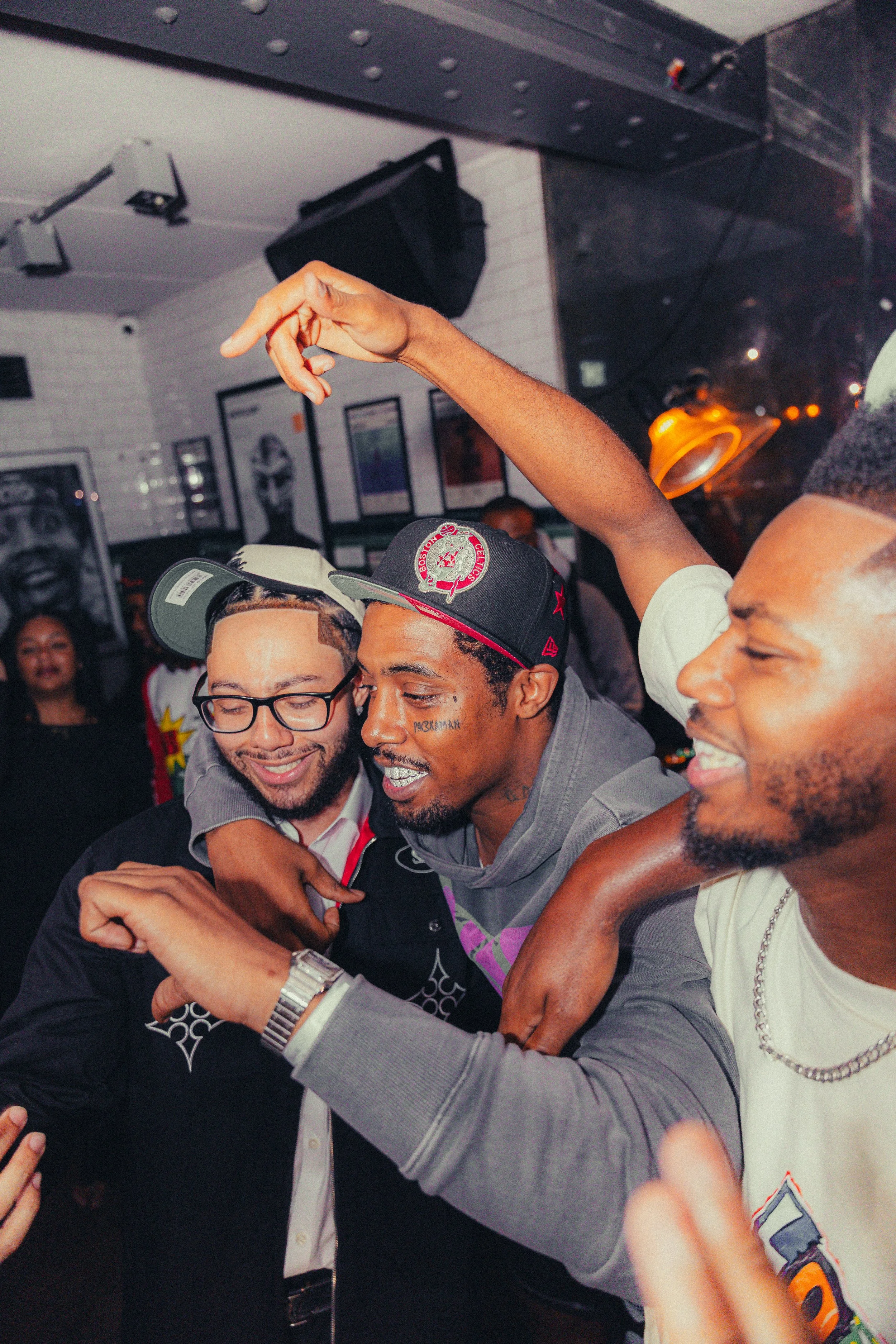 Three men are celebrating and having fun at a social gathering or party, with arm-in-arm expressions and smiling faces.