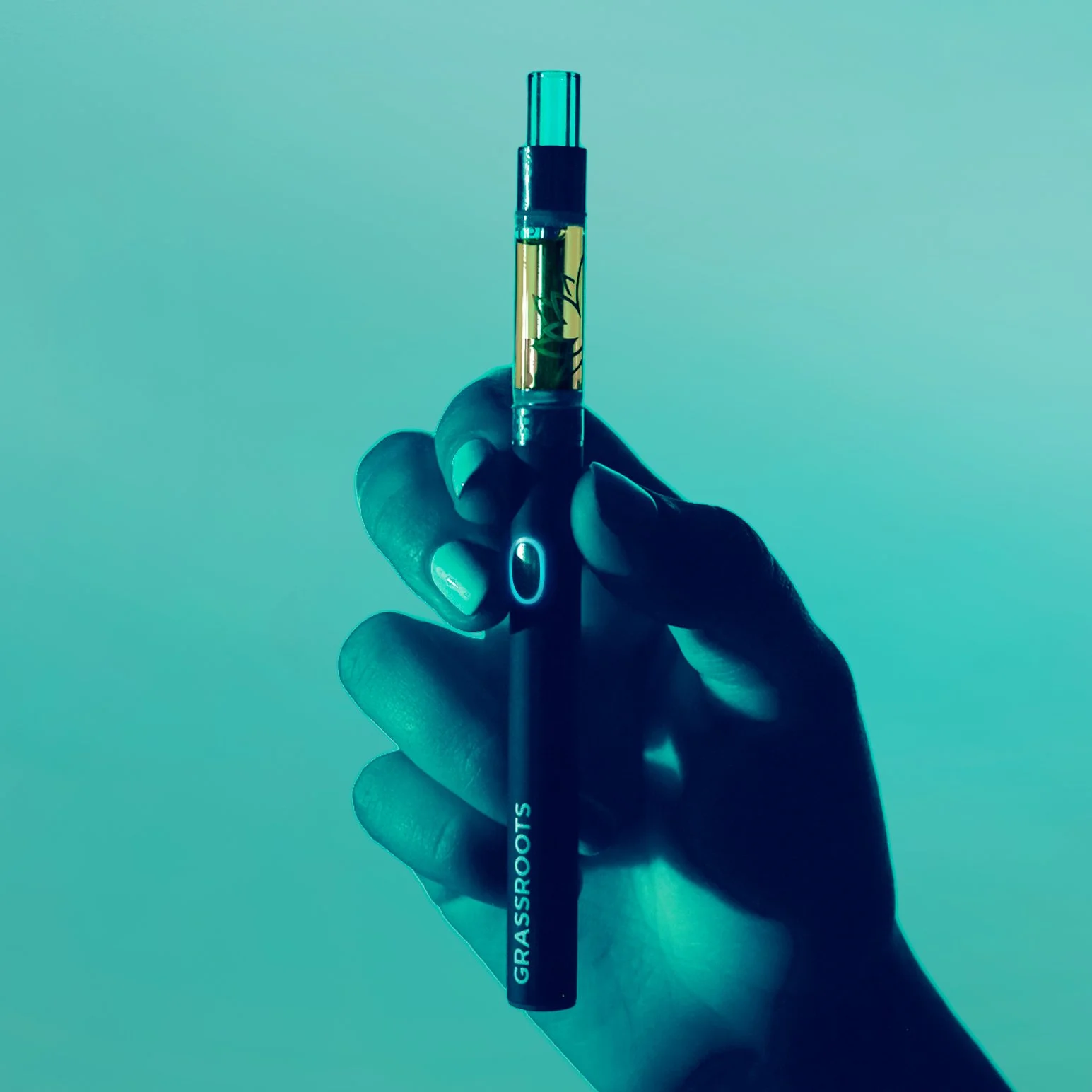 A hand holds a vape pen with a transparent chamber showing liquid inside. The vape pen has the brand name 'GRASSROOTS' on it. The background is a gradient of teal and light blue.
